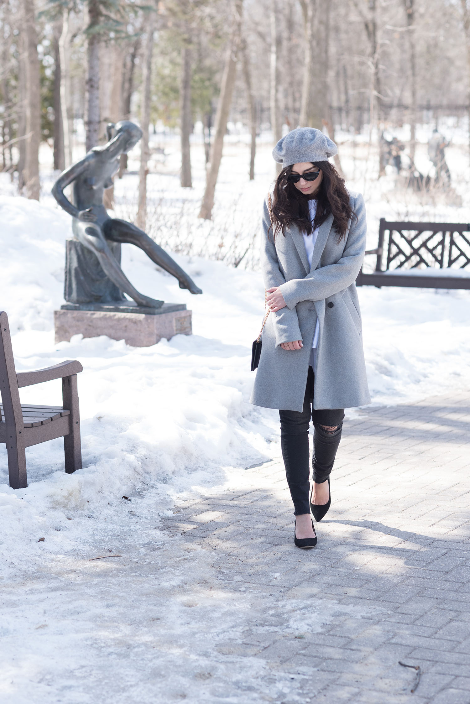 Fashion blogger Cee Fardoe of Coco & Vera walks through Leo Mol sculpture garden wearing a grey Zara coat and Mavi black skinny jeans