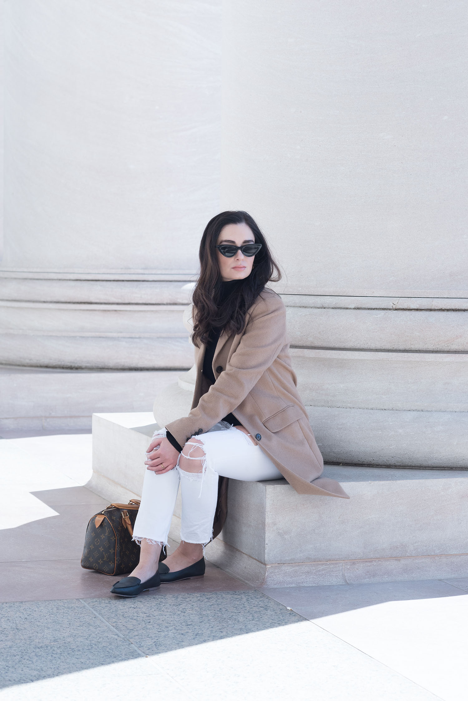 Canadian fashion blogger Cee Fardoe of Cooc & Vera sits outside of the National Gallery of Art in Washington DC, wearing a Uniqlo camel coat and J. Crew leather moccasins