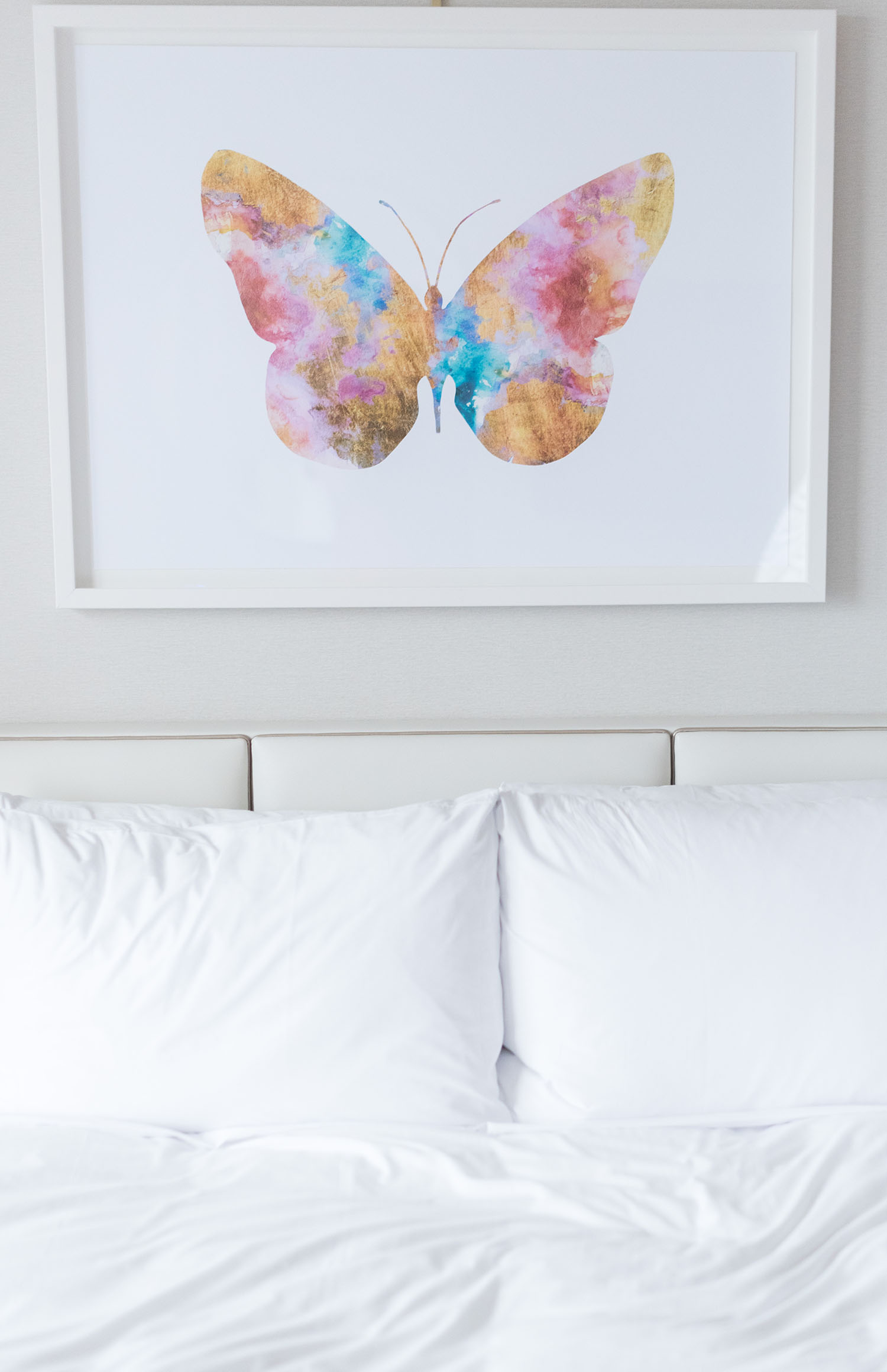 A multi-coloured butterfly print hangs above a bed at the JW Marriott Parq Vancouver hotel, as captured by Winnipeg travel blogger Cee Fardoe of Coco & Vera