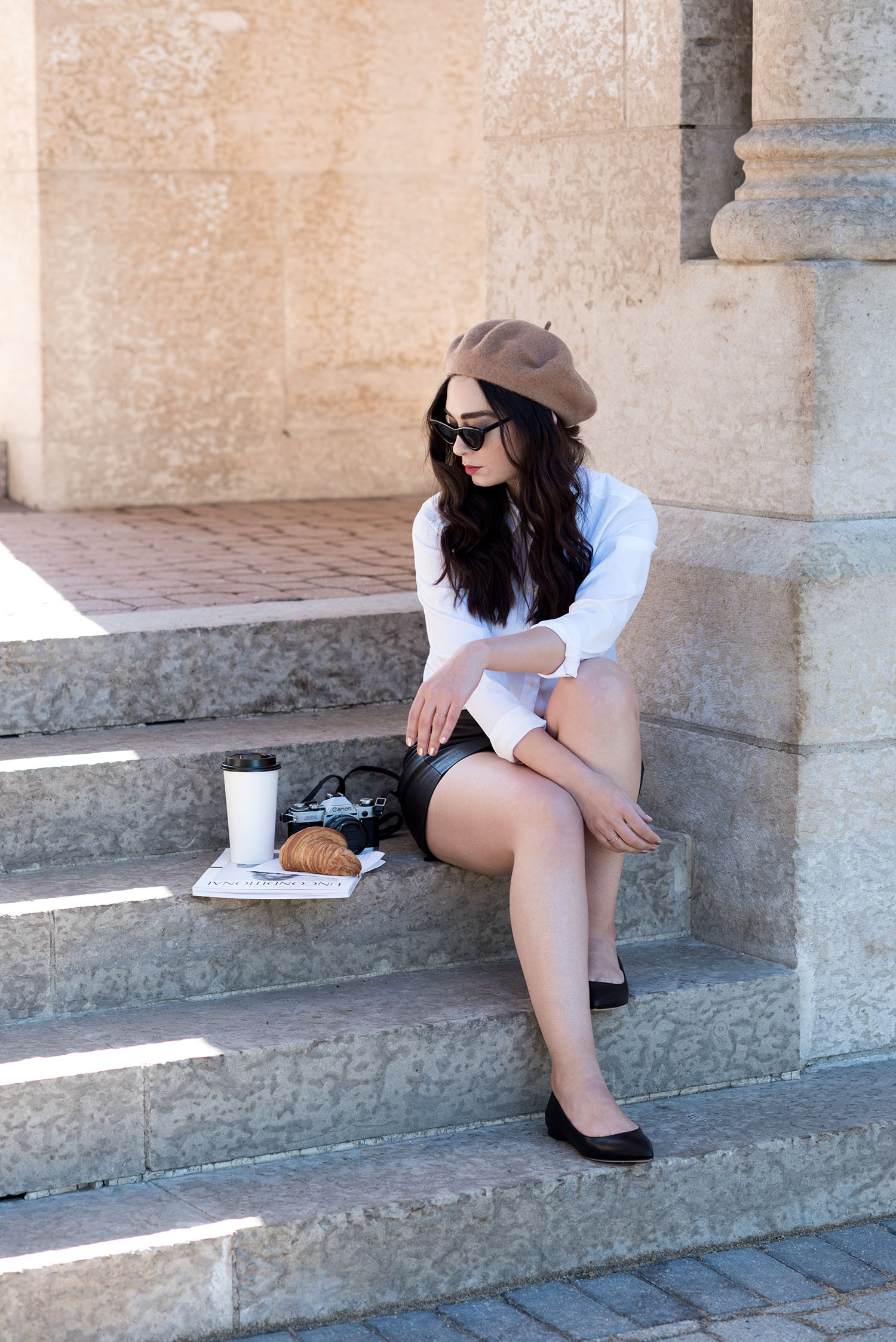 Top fashion blogger Cee Fardoe of Coco & Vera sits on the stairs at Saint-Boniface cathedral wearing a white Uniqlo blouse and M Gemi flats
