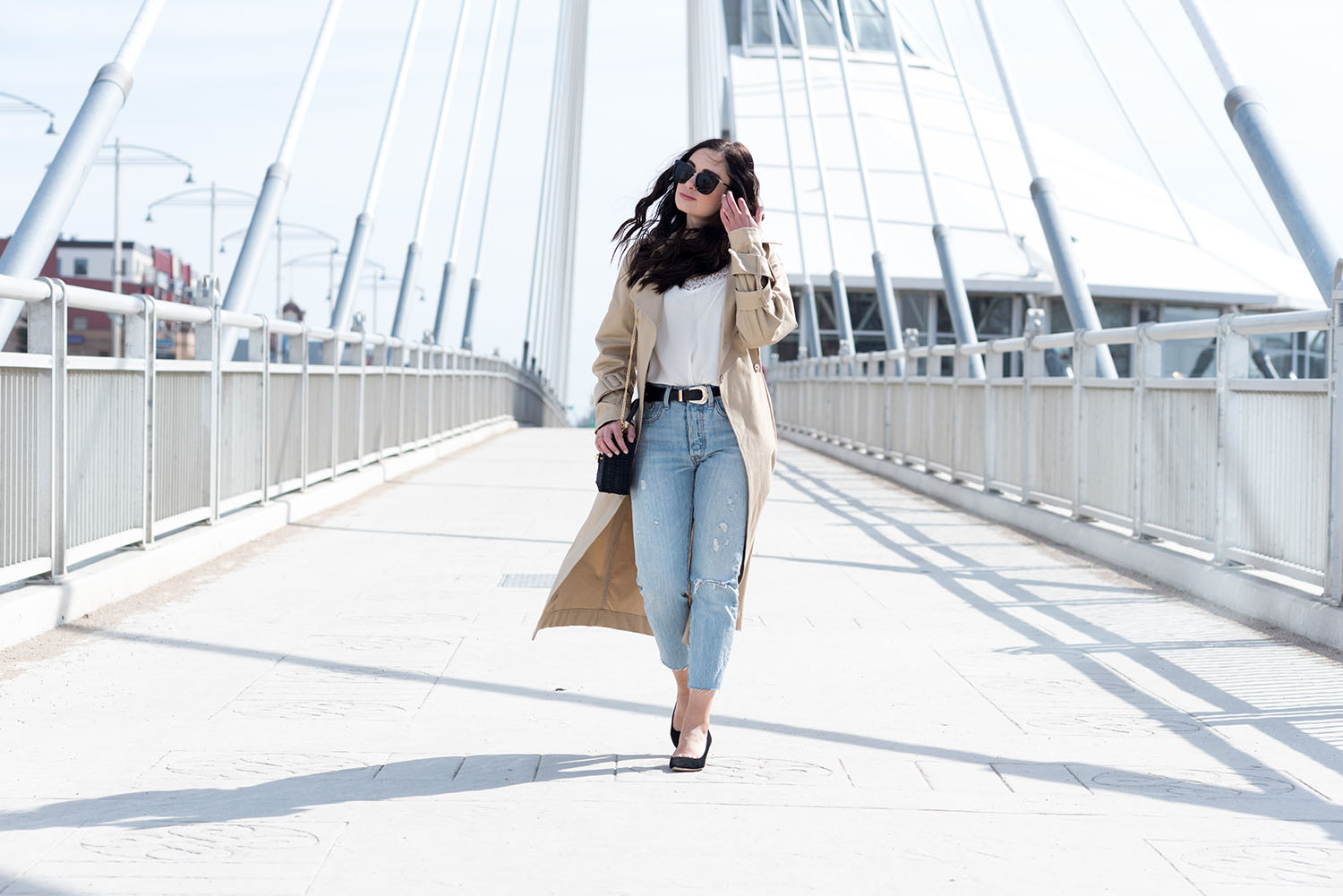 Fashion blogger Cee Fardoe of Cooc & Vera walks across Louis Riel bridge in Winnipeg wearing an H&M trench coat and Levi's 501 skinny jeans