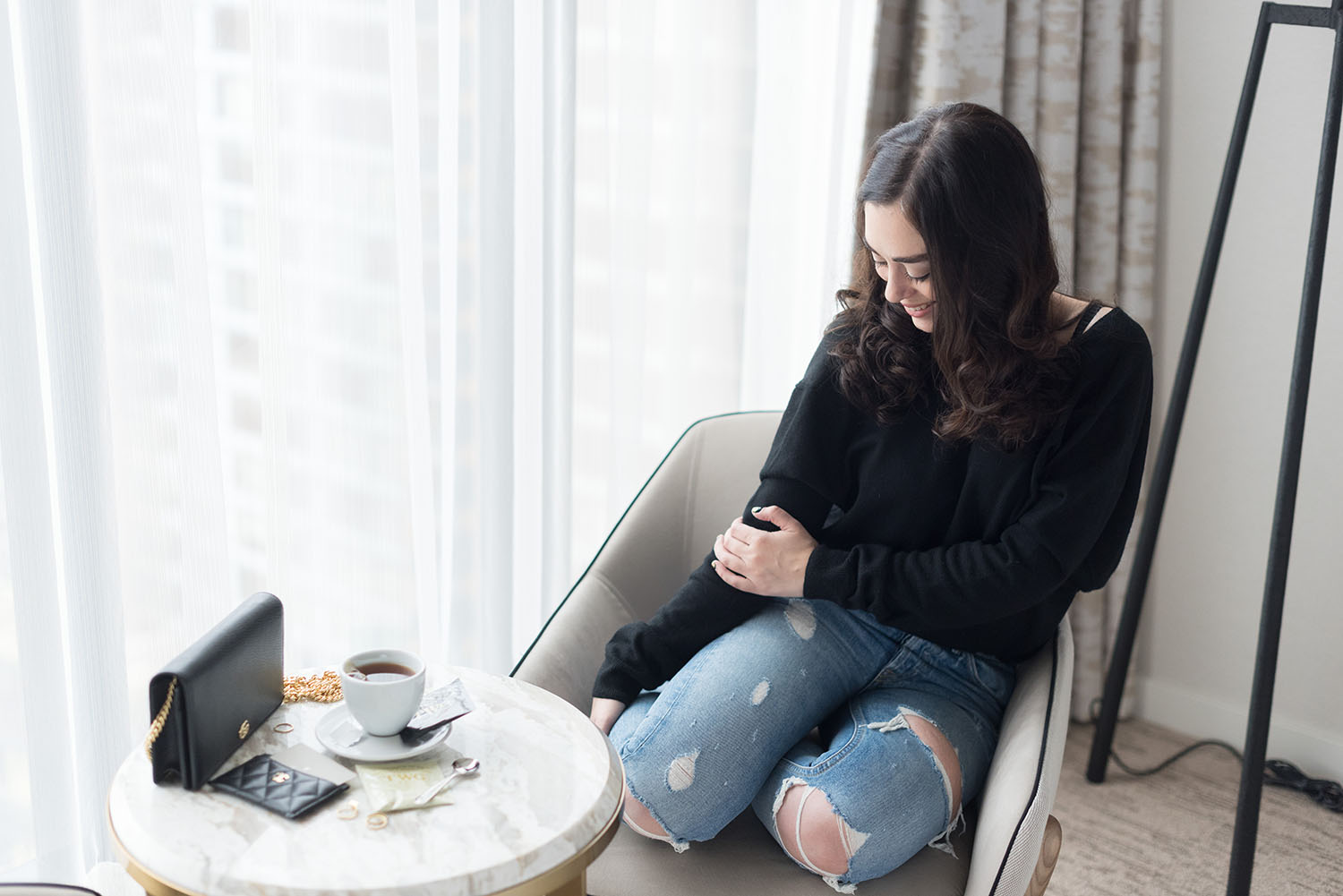 Winnipeg travel blogger Cee Fardoe of Coco & Vera sits in her room at the JW Marriott hotel at Parq Vancouver,w wearing and ASOS sweater and drinking TWG tea