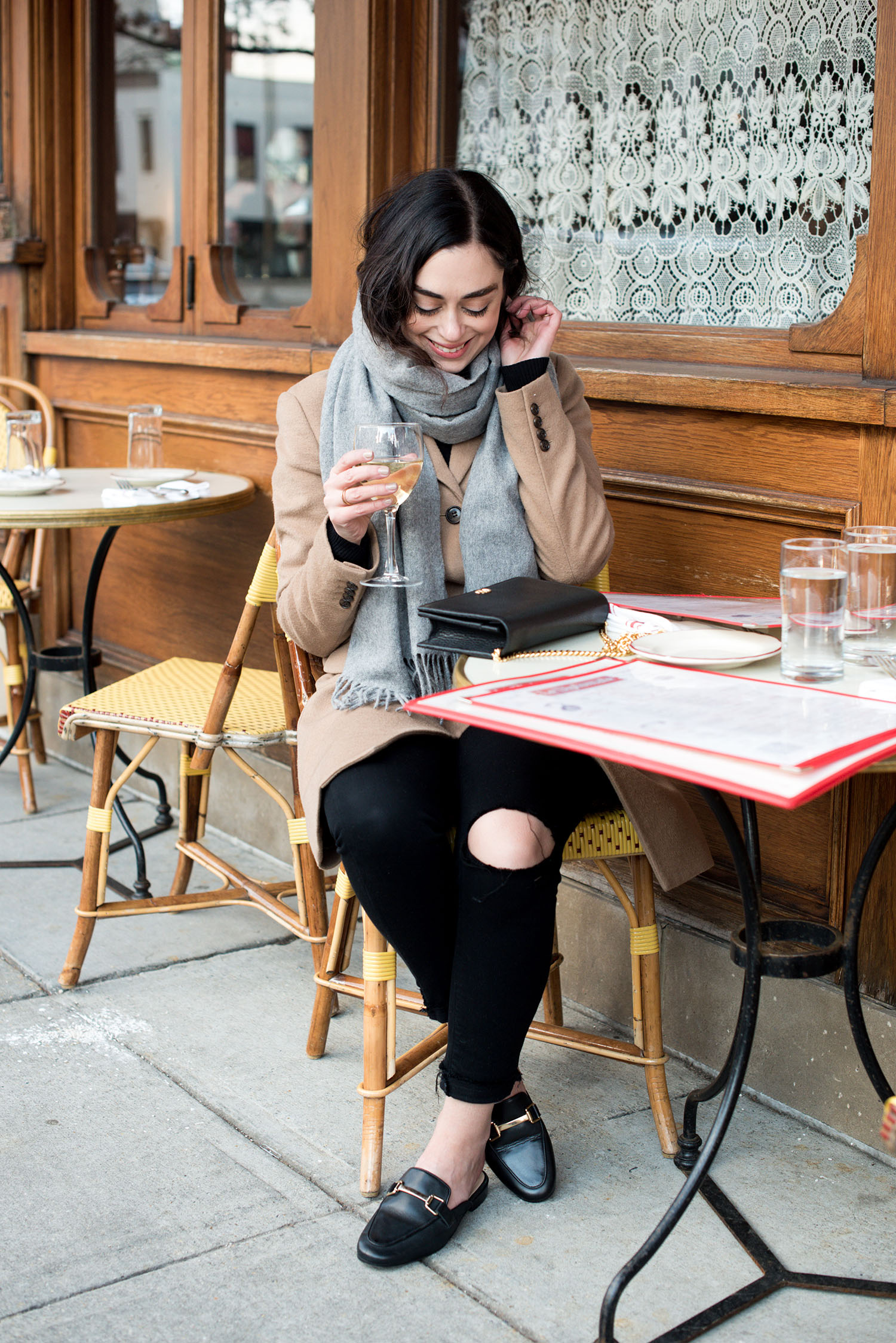 Canadian fashion blogger Cee Fardoe of Coco & Vera drinks wine at Le Diplomate wearing a Uniqlo camel coat and Paige black jeans