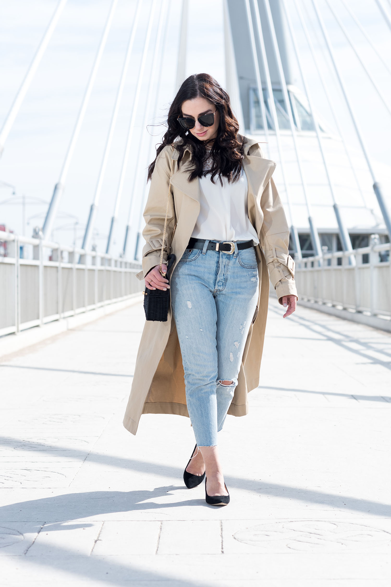 Winnipeg fashion blogger Cee Fardoe of Coco & Vera walks on Louis Riel bridge wearing an H&M trench coat and Levi's 501 skinny jeans