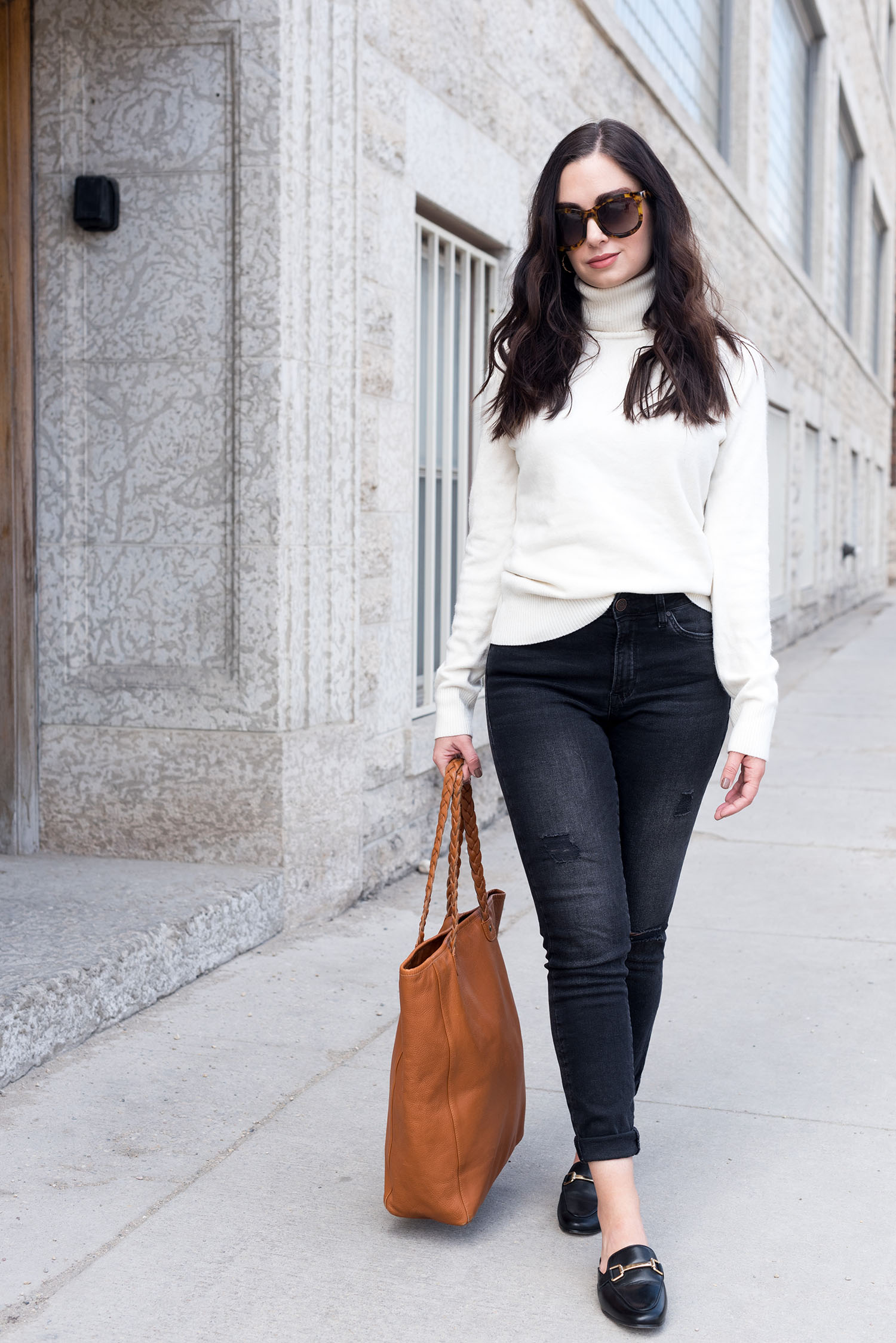 Top Winnipeg fashion blogger Cee Fardoe of Coco & Vera walks outside Mall Plaza wearing black Mavi jeans and a cream sweater from Noul