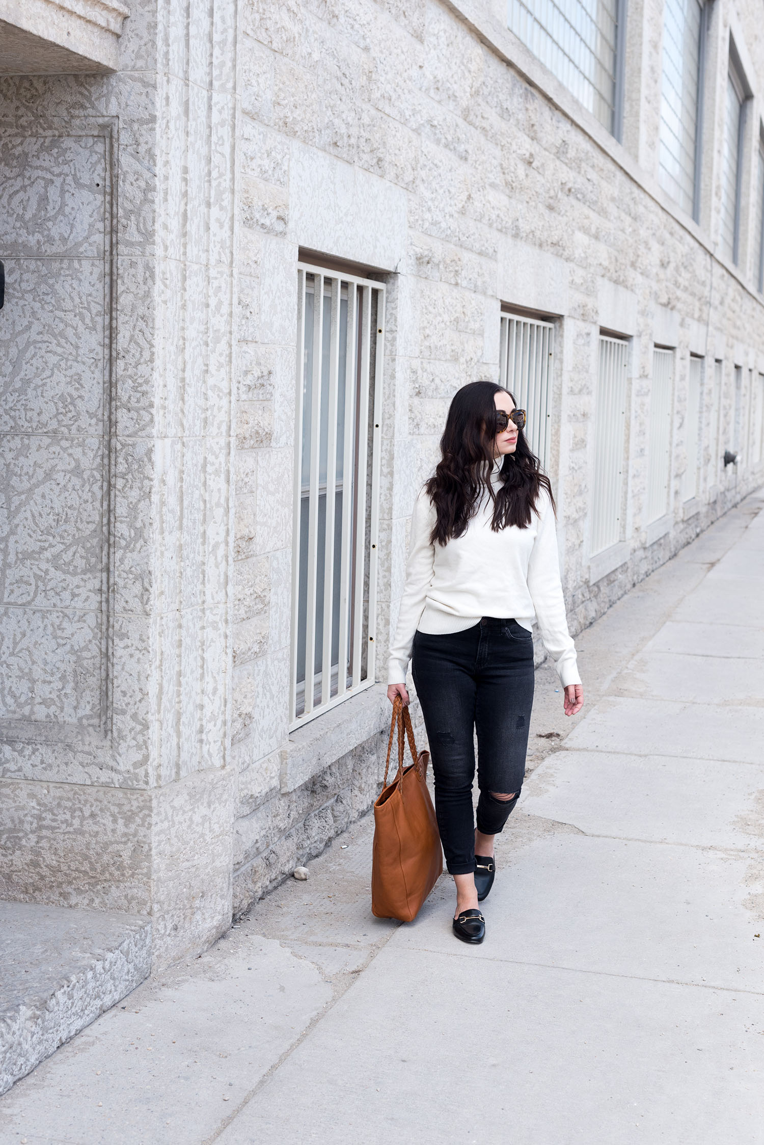 Fashion blogger Cee Fardoe of Coco & Vera walks in downtown Winnipeg wearing a cream sweater from Noul and black jeans from Mavi