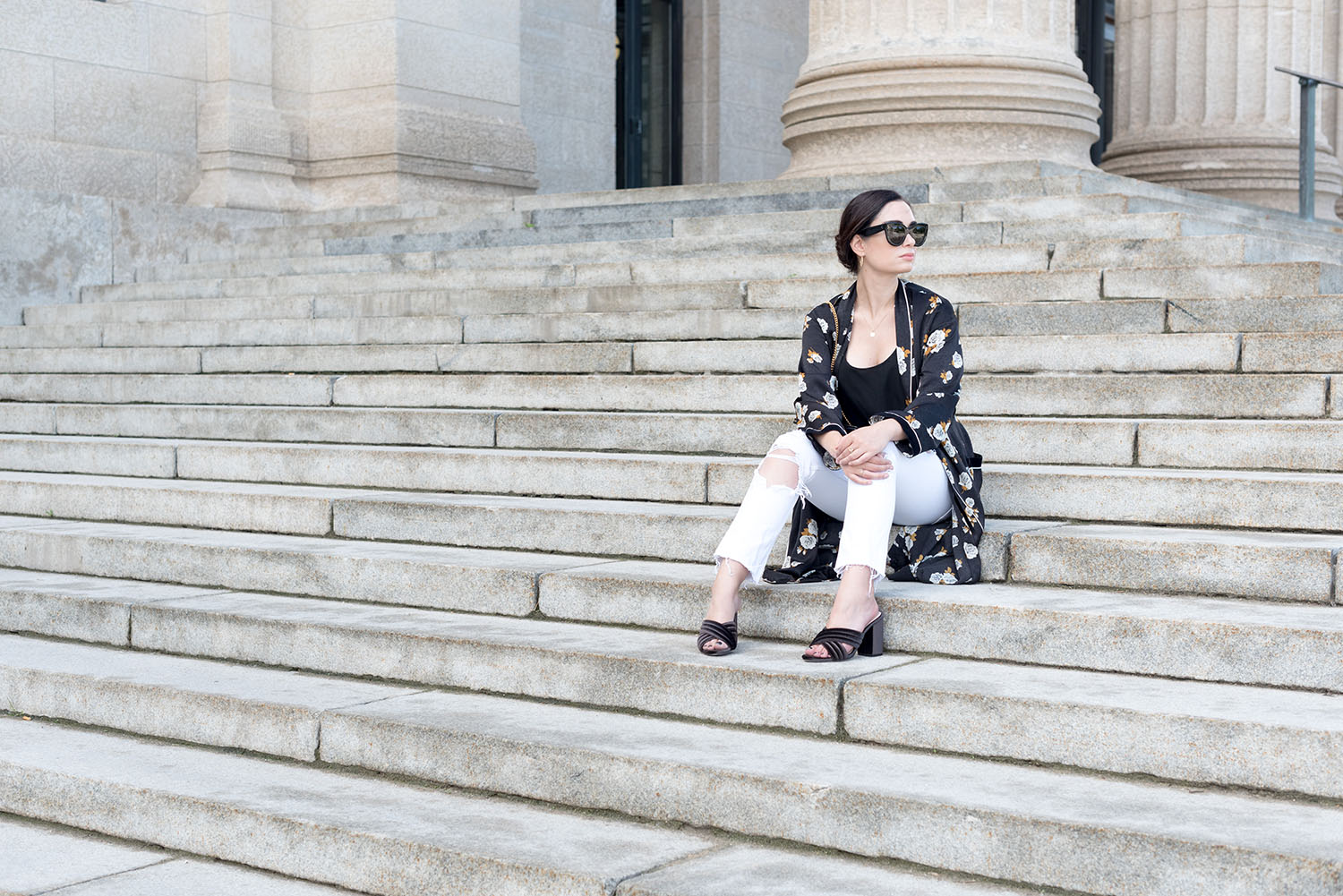 Top Canadian fashion blogger Cee Fardoe of Coco & Vera sits on the steps of the Manitoba legislature wearing a Zara floral kimono and black Raye mules