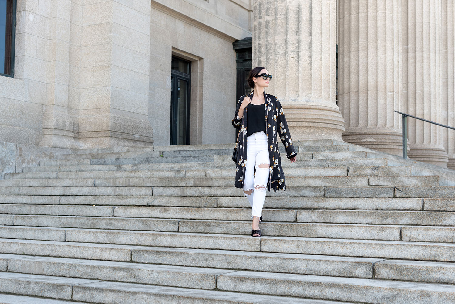 Top Winnipeg fashion blogger Cee Fardoe of Coco & Vera walks down the stairs at the Manitoba Legislature wearing a Zara black kimono and white Grlfrnd jeans