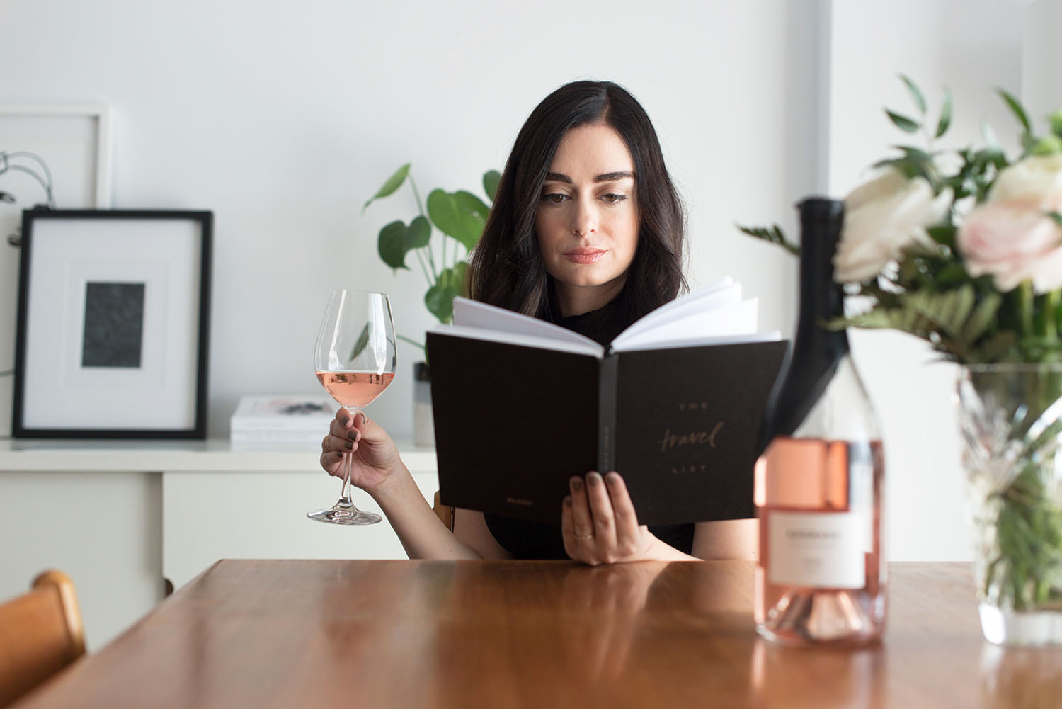 Top Winnipeg fashion blogger Cee Fardoe of Coco & Vera reads while drinking Adorada rose wine in her dining room