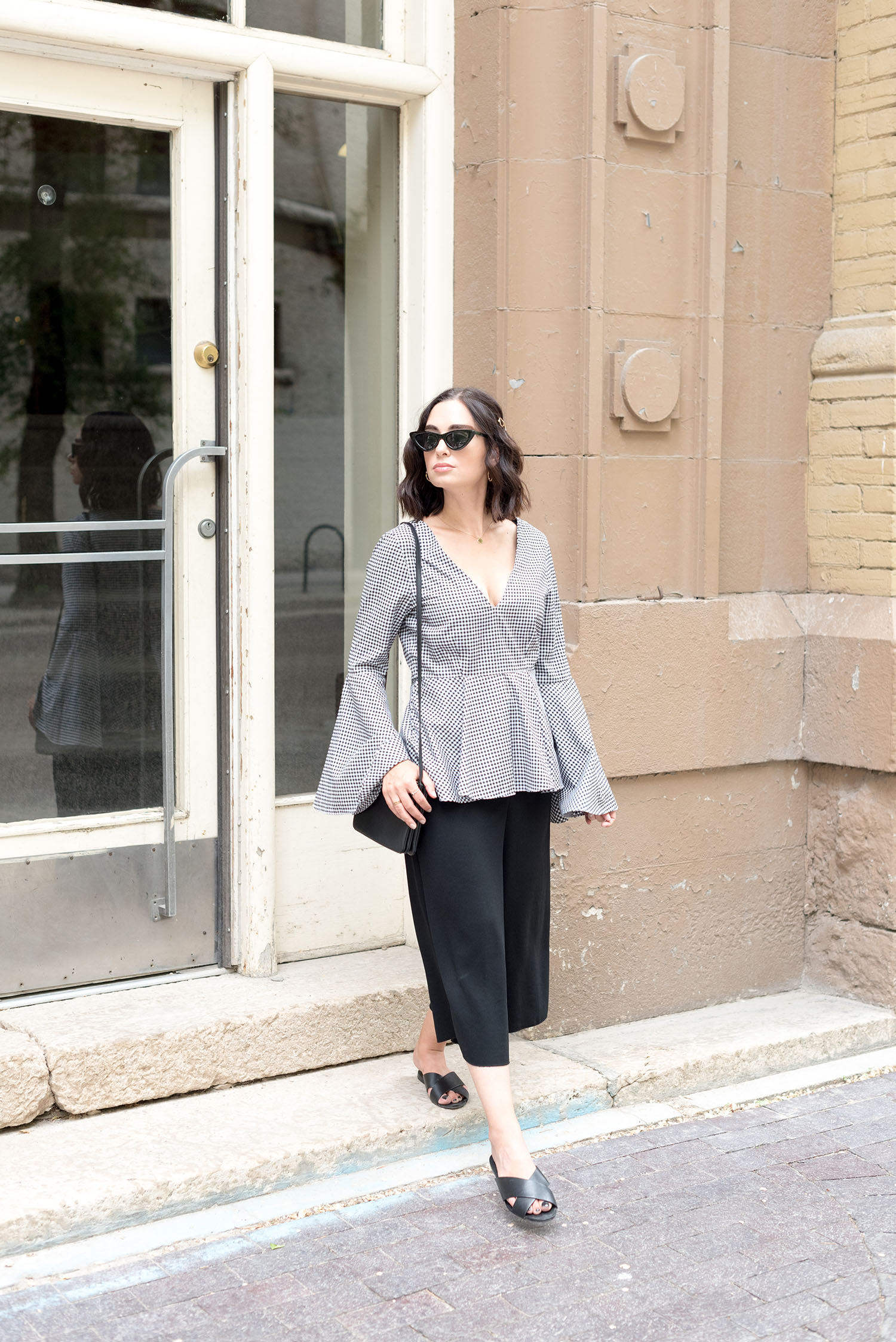 Top Winnipeg fashion blogger Cee Fardoe of Coco & Vera walks in The Exchange District wearing a L'academia blouse and carrying a Celine trio bag
