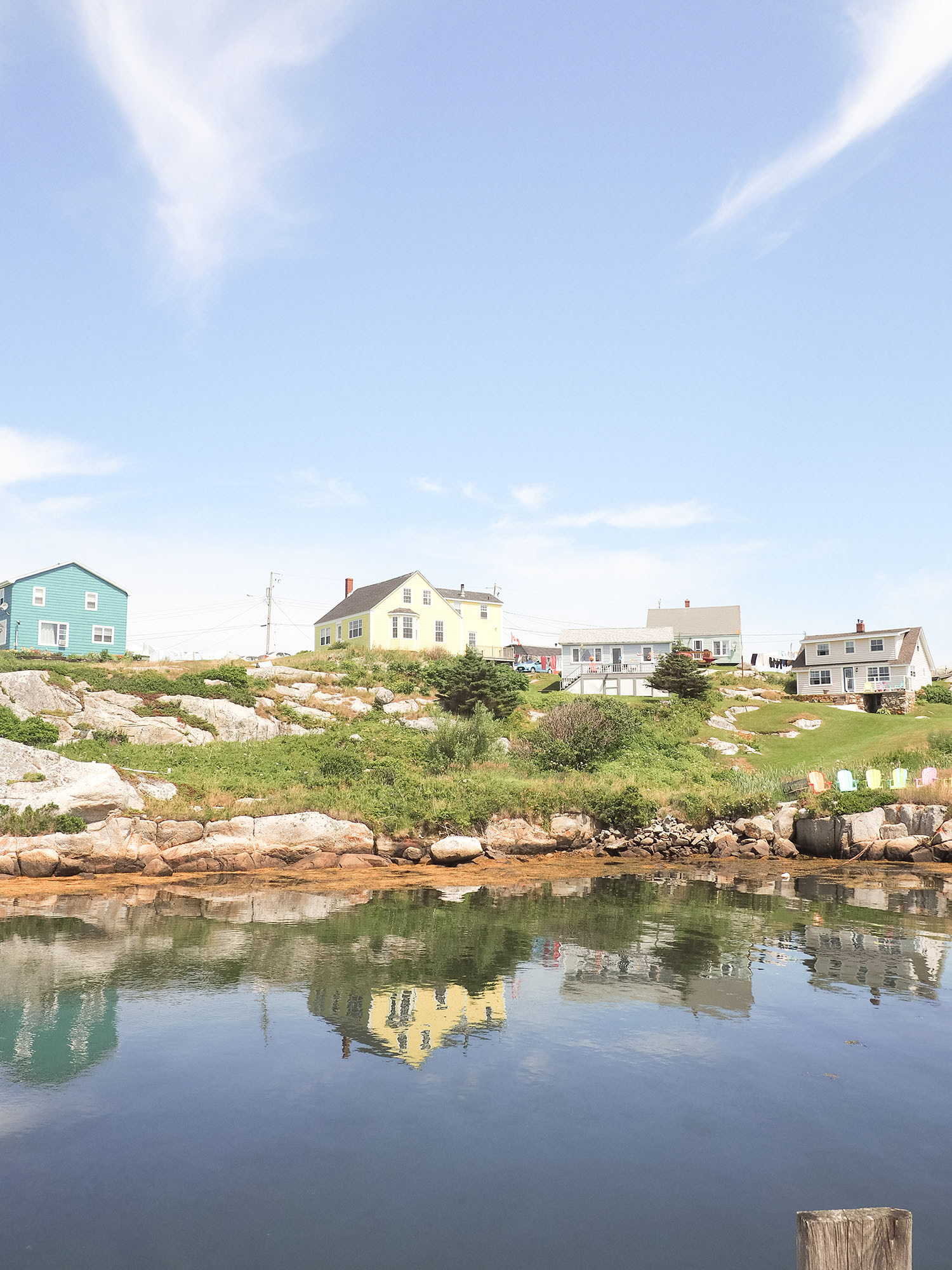 Houses on a hill reflected in the bay at Peggy's Cove, as captured by top Winnipeg travel blogger Cee Fardoe of Coco & Vera