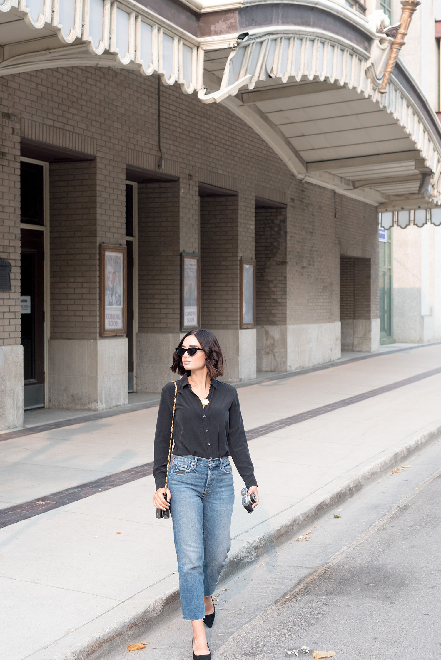 Top Winnipeg fashion blogger Cee Fardoe of Coco & Vera walks outside Pantages Playhouse wearing Grlfrnd Helena jeans and an Everlane silk blouse