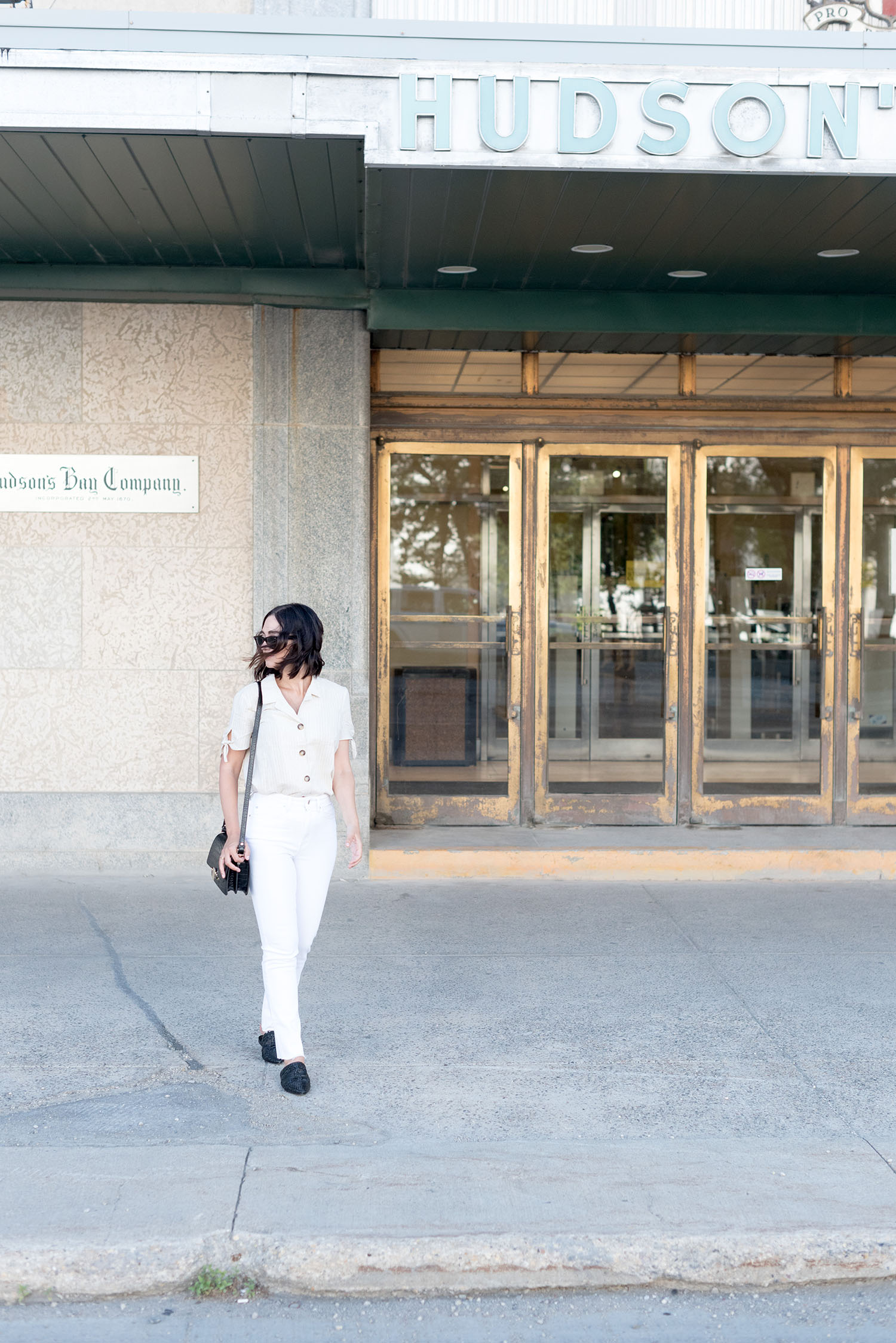 Top Canadian fashion blogger Cee Fardoe of Coco & Vera walks outside The Bay Downtown in Winnipeg wearing Mango white jeans