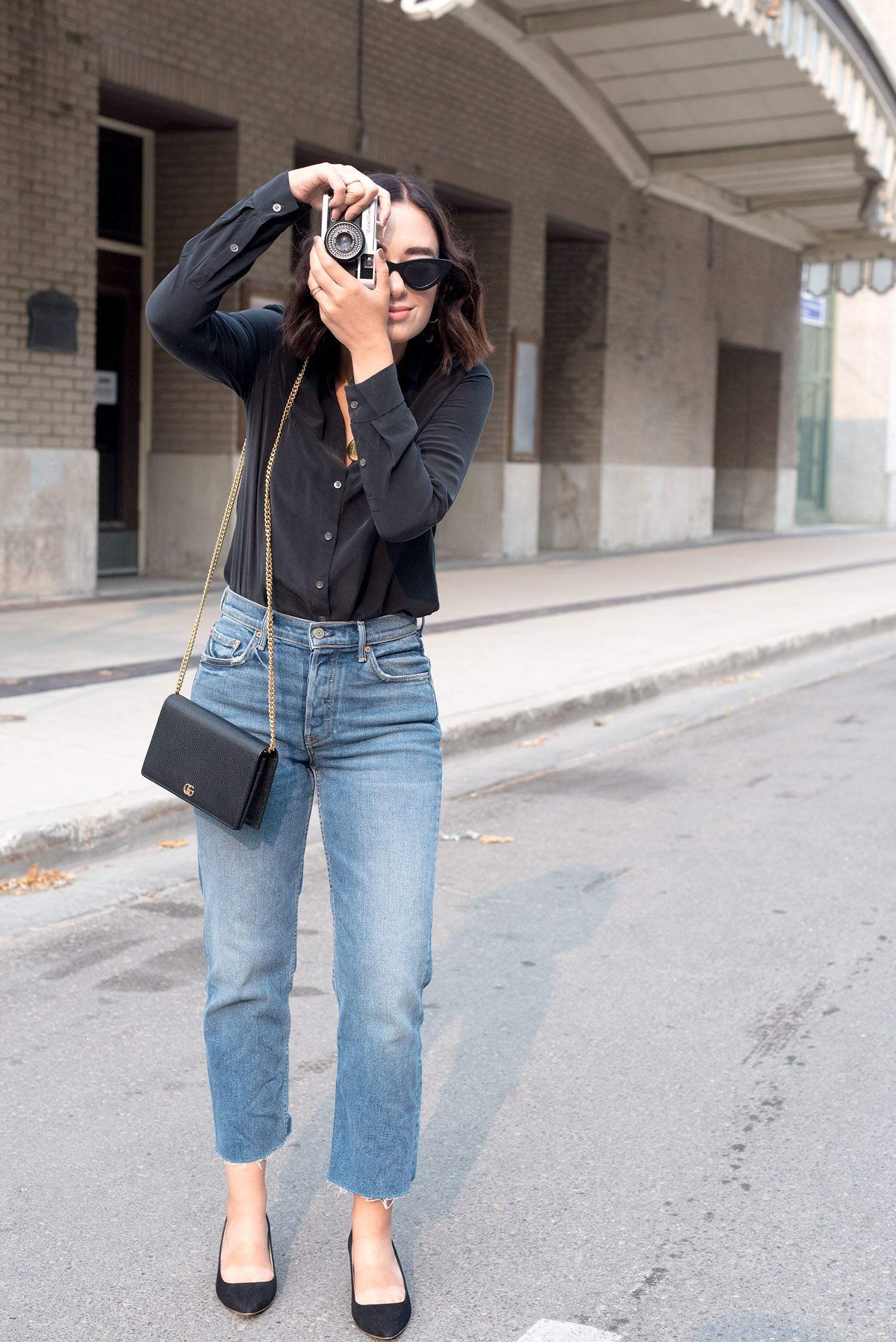 Top Winnipeg fashion blogger Cee Fardoe of Coco & Vera talks a photo with an Olympus Trip camera while wearing Grlfrnd Helena jeans and carrying a Gucci Marmont handbag