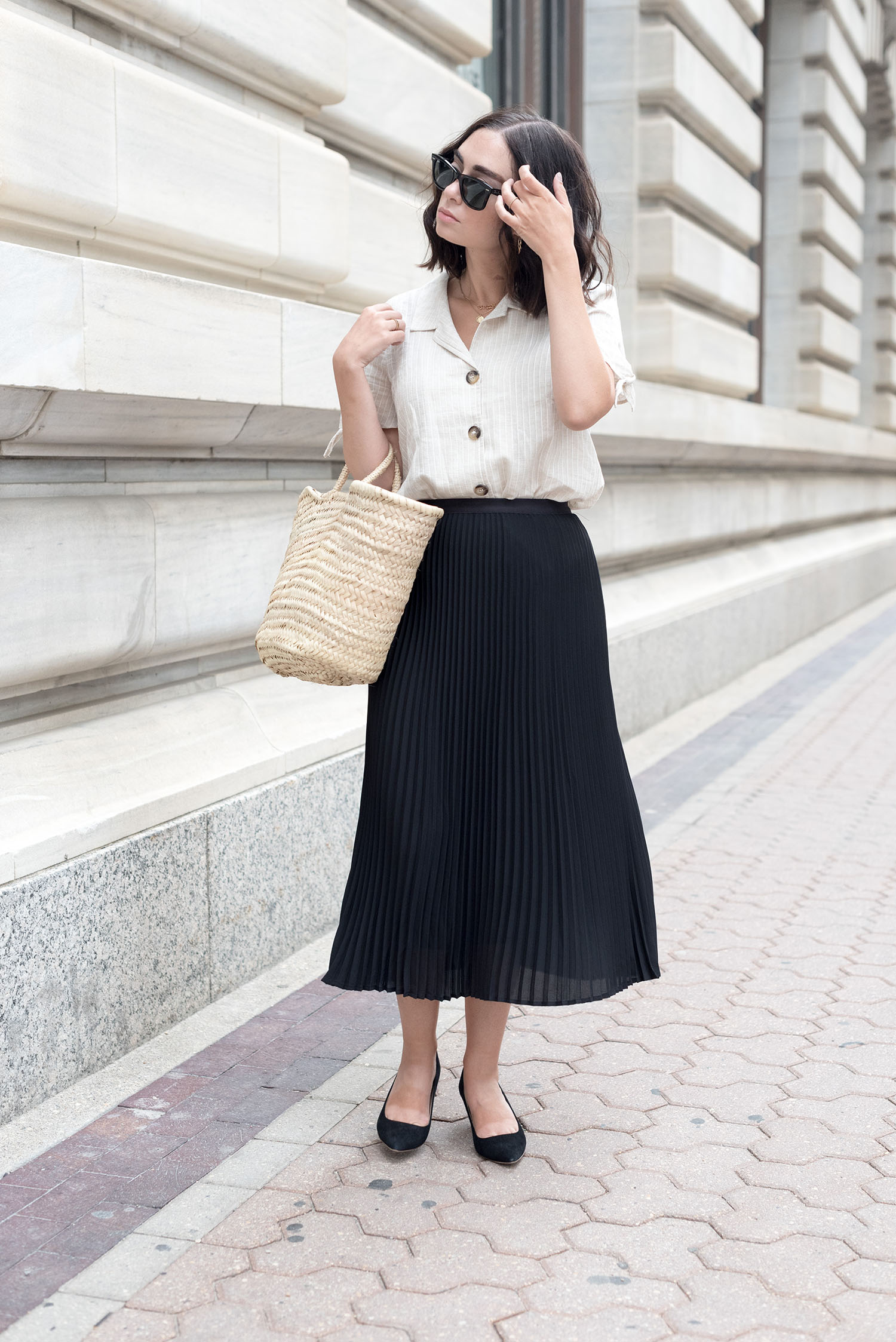 Top Winnipeg fashion blogger Cee Fardoe of Coco & Vera walks through the Exchange District wearing a black pleated skirt from Aritzia and a linen blouse from Mango