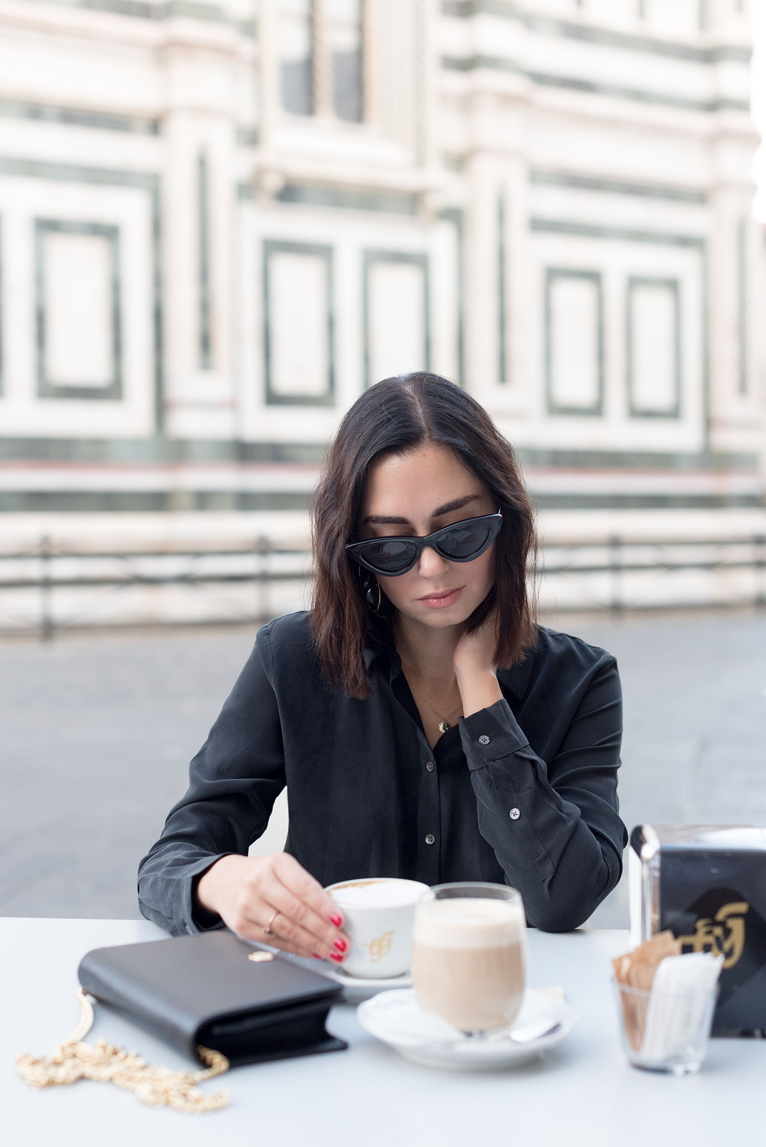 Portrait of top Canadian fashion blogger Cee Fardoe of Coco & Vera drinking cappuccino outside the Duomo in Florence, wearing Zara sunglasses and an Everlane blouse