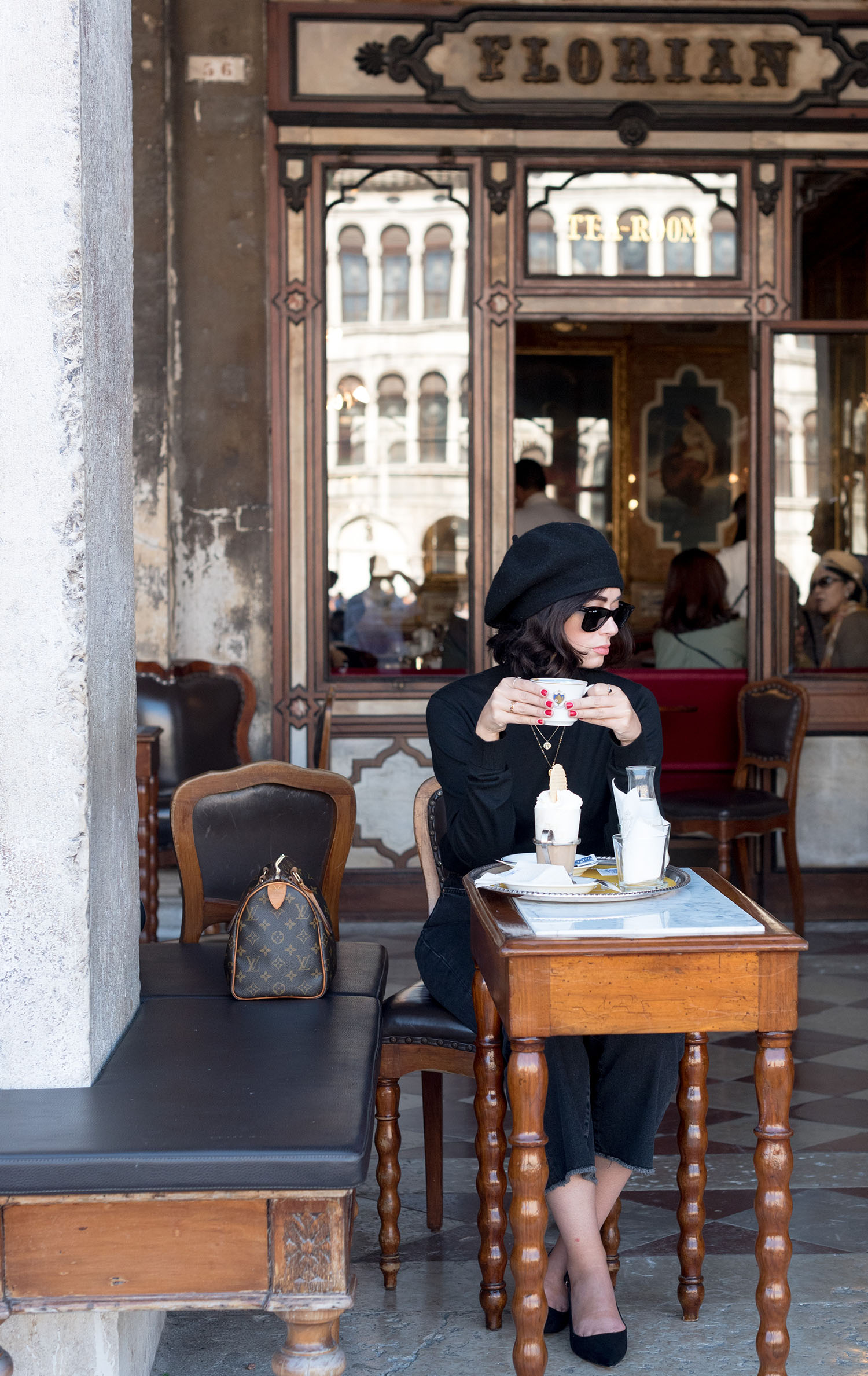 Top Winnipeg fashion blogger Cee Fardoe of Coco & Vera sits drinking coffee at Caffe Floriane in Venice wearing an Anthropologie Bonnie beret and RayBan Wayfarer sunglasses