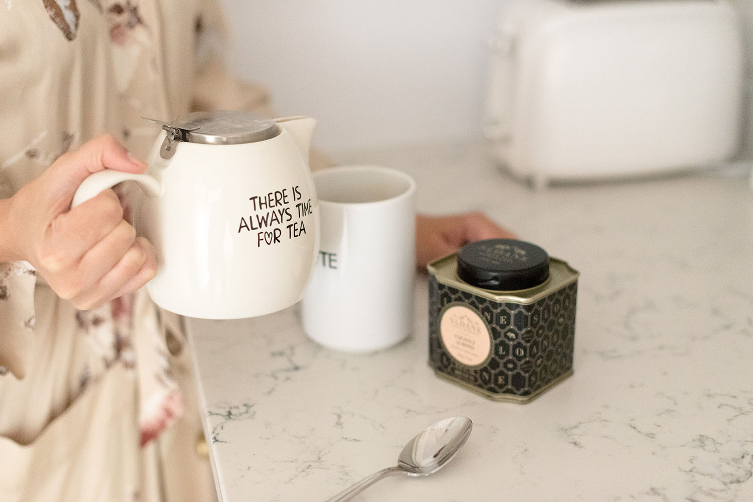 Top Winnipeg lifestyle blogger Cee Fardoe of Coco & Vera pours tea in her kitchen, using a white Chapters Indigo teapot
