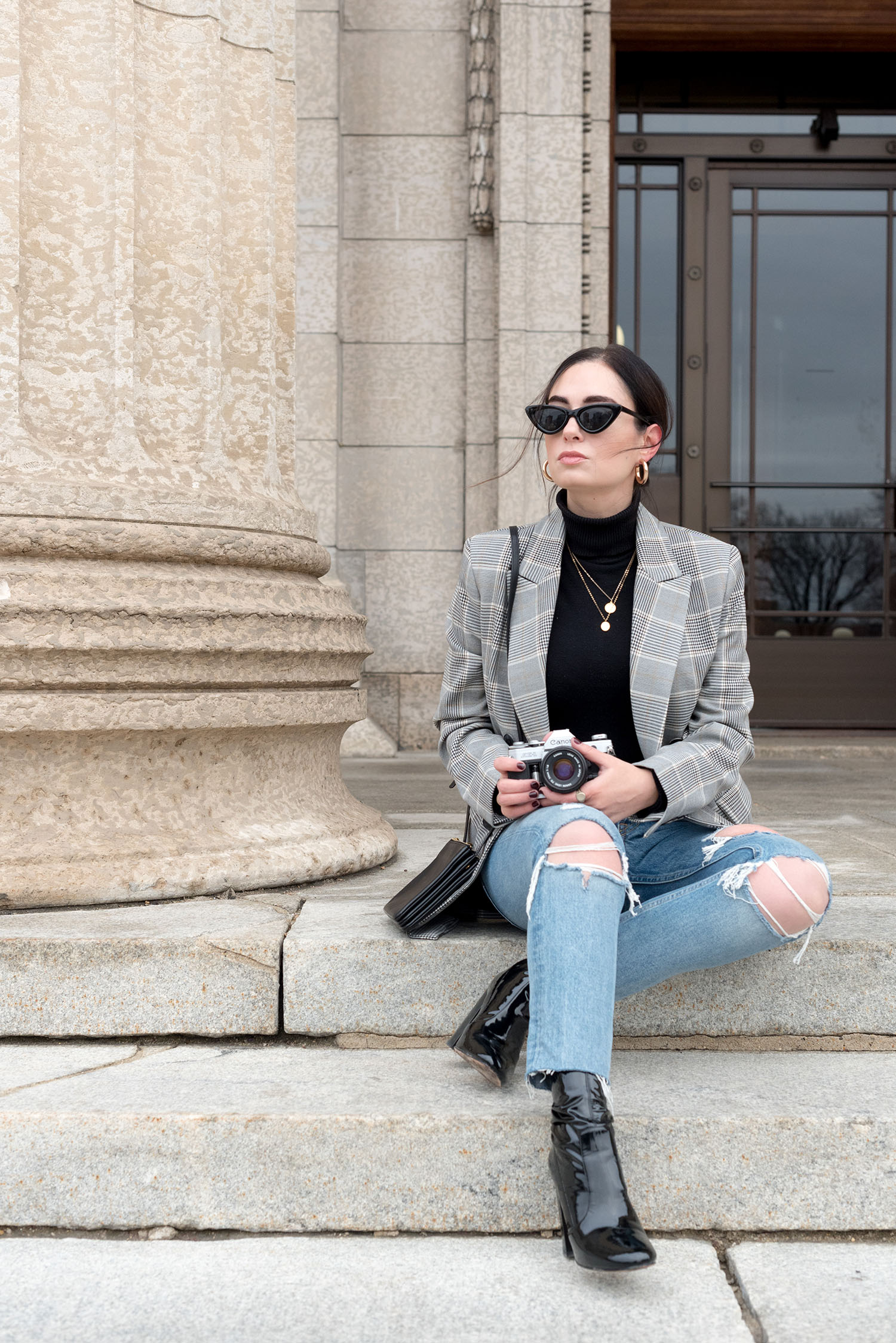 Top Winnipeg fashion blogger Cee Fardoe of Coco & Vera sits on the stairs of the Manitoba Legislature wearing Grlfrnd blue jeans and a Le Chateau black turtleneck sweater