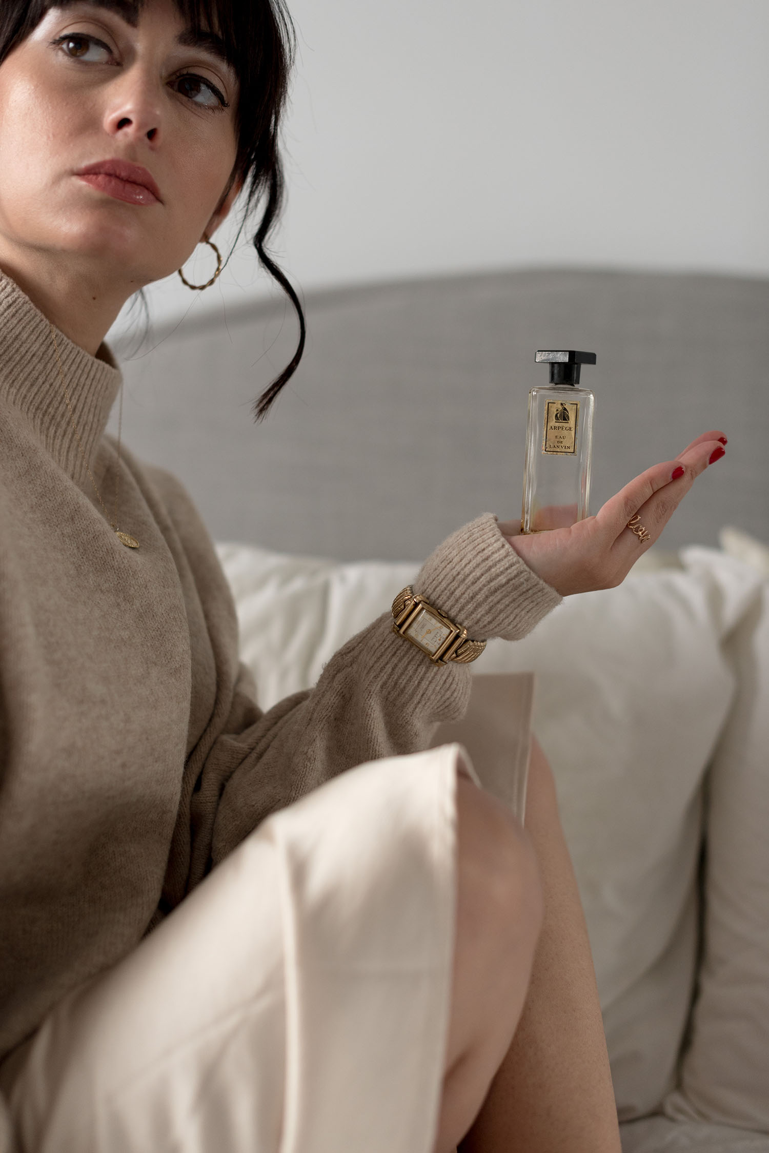 Portrait of top Canadian fashion blogger Cee Fardoe of Coco & Vera, holding a vintage bottle of Lanvin's Arpege perfume and wearing an H&M beige sweater