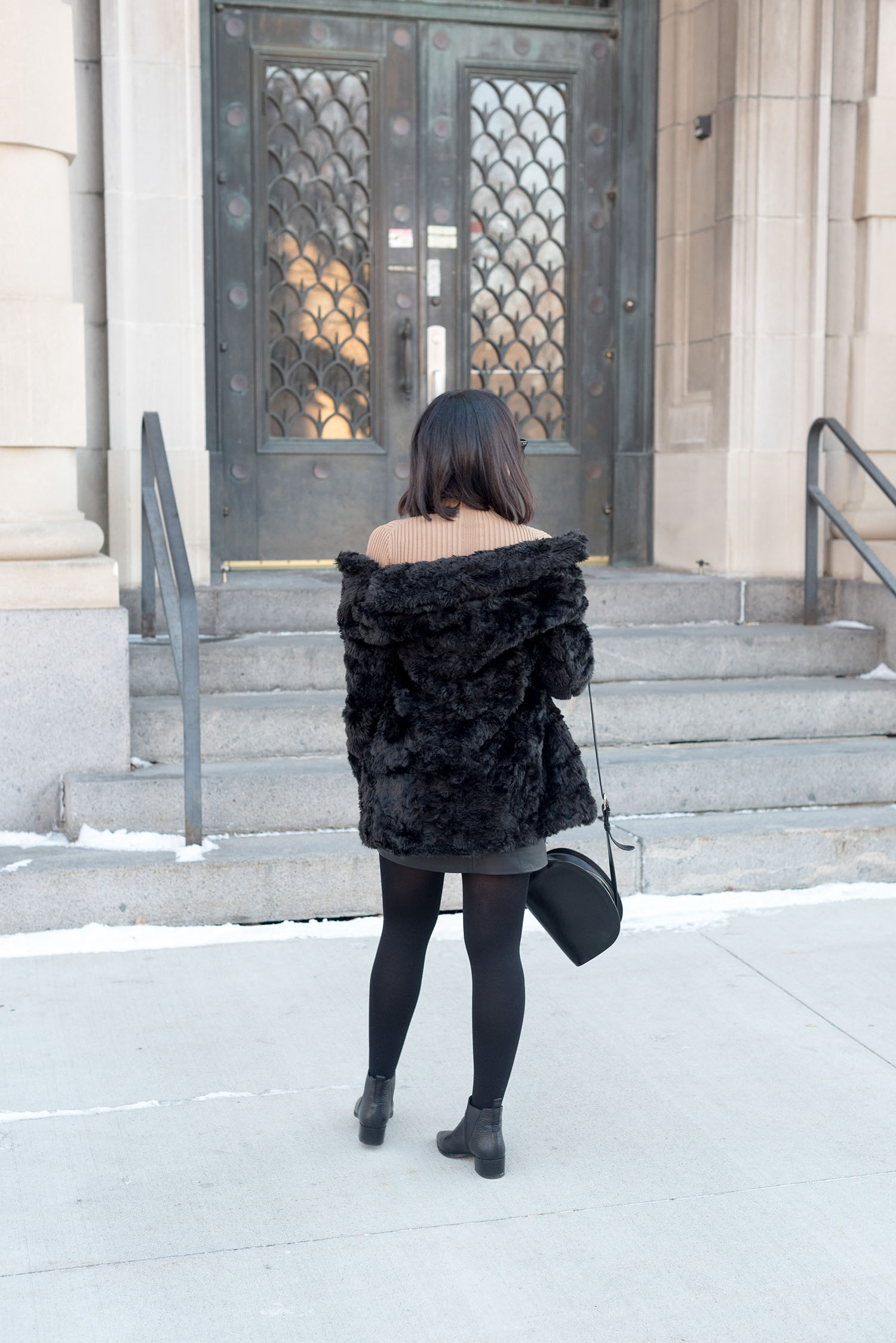 Top Canadian fashion blogger Cee Fardoe of Coco & Vera wears a Le Chateau faux fur coat and carries and APC half-moon bag in Grand Forks, North Dakota