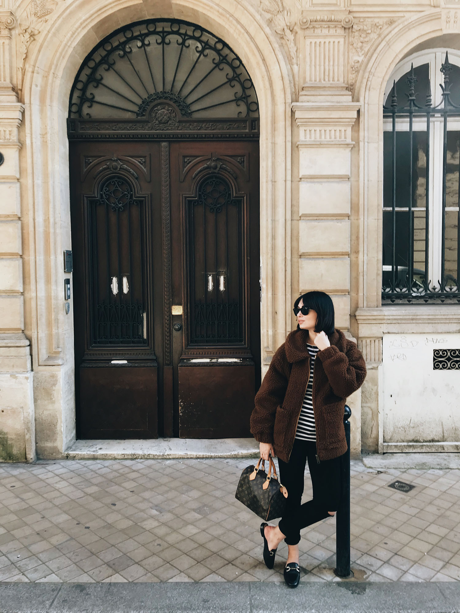 Top Winnipeg fashion blogger Cee Fardoe of Coco & Vera stands on rue des Bahutiers in Bordeaux wearing Mavi jeans and carrying a Louis Vuitton handbag