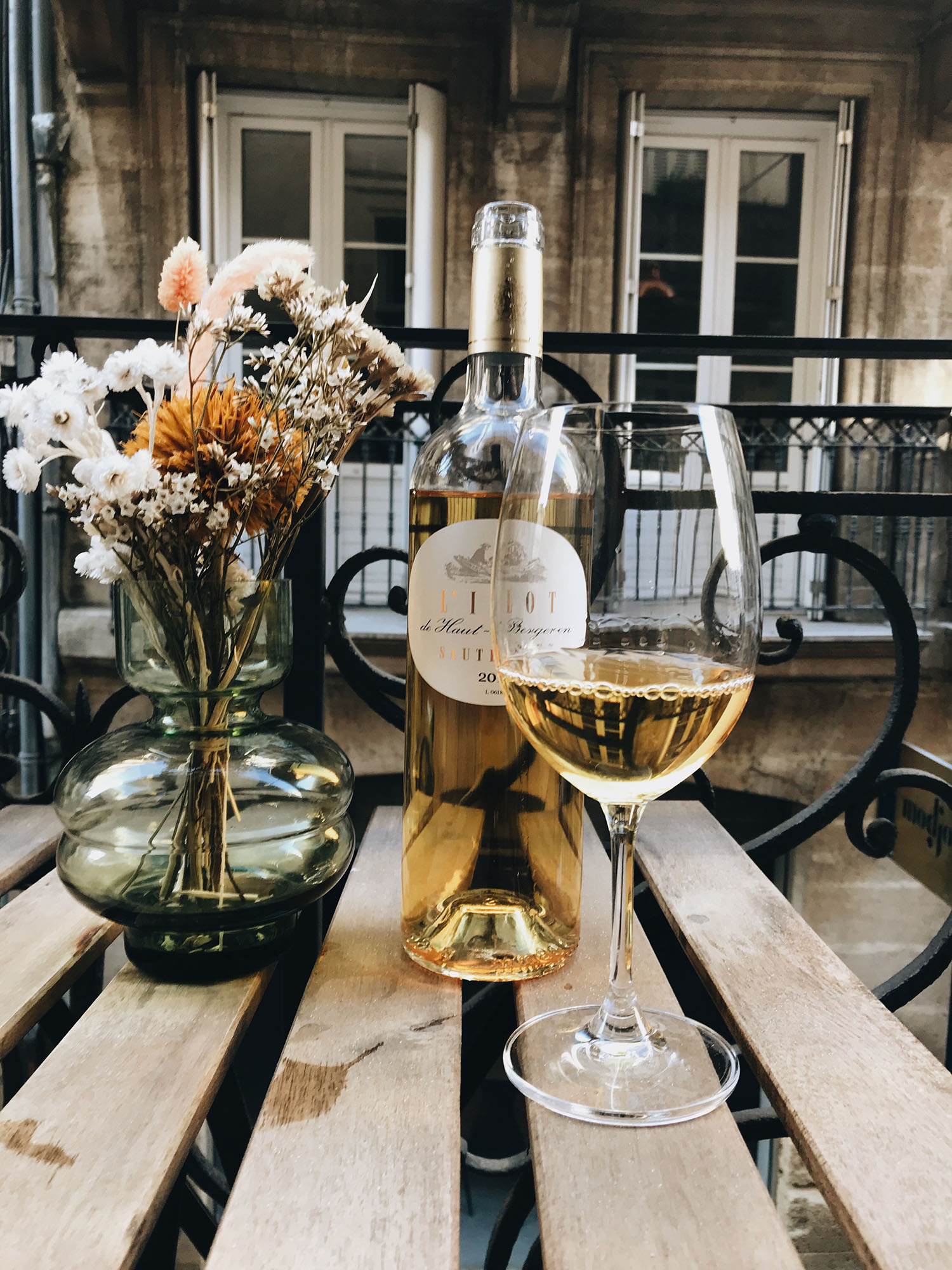 A bottle and glass of white wine on a balcony table at La Maison Fernand in Bordeaux, France, as captured by top Canadian travel blogger Cee Fardoe of Coco & Vera