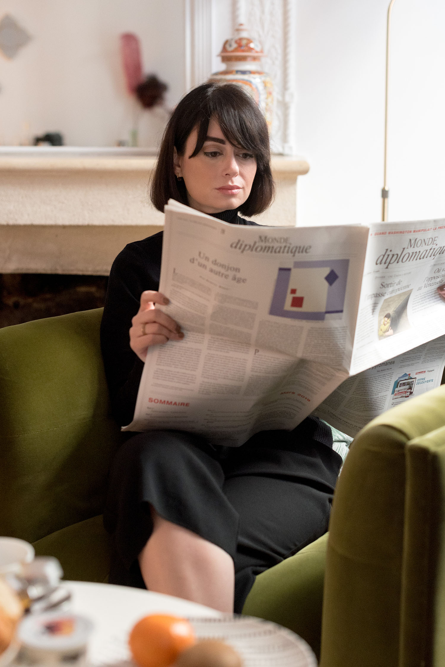 Top Canadian fashion blogger Cee Fardoe of Coco & Vera reads Le Monde Diplomatique at La Maison Fernand in Bordeaux, wearing Aritzia culottes and a black turtleneck sweater