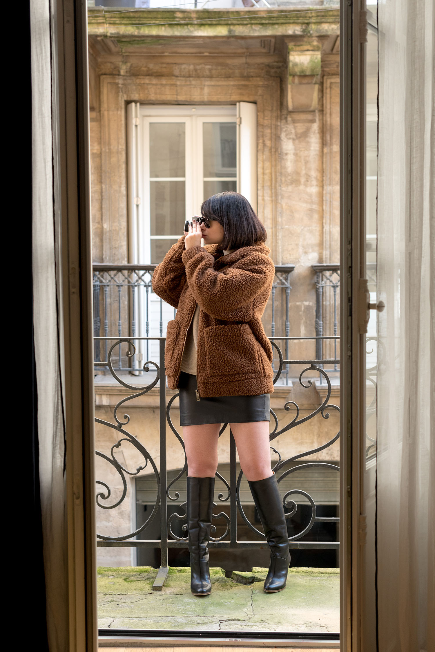 Top Winnipeg fashion blogger Cee Fardoe of Coco & Vera stands on a balcony at Maison Fernand in Bordeaux wearing a Sezane leather skirt and Garage Clothing teddy coat