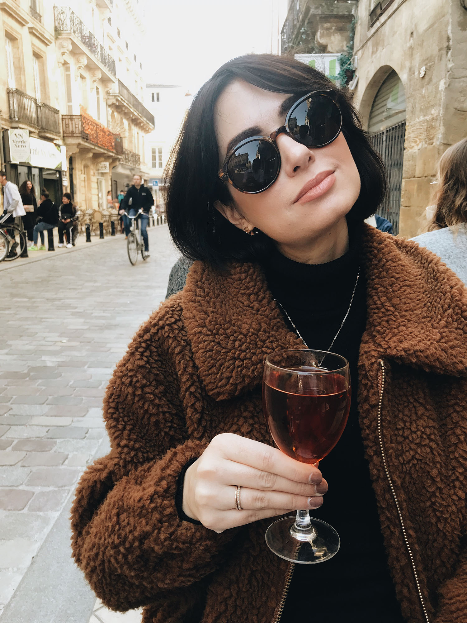 Top Winnipeg travel blogger Cee Fardoe of Coco & Vera sits at a cafe in Bordeaux, drinking kir