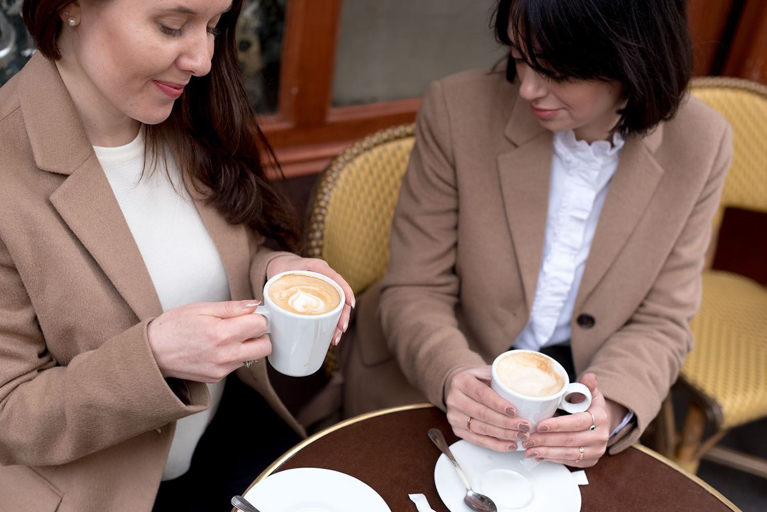Top Canadian fashion bloggers Cee Fardoe of Coco & Vera and Lyndi Barrett of Style calling drinks cafe creme in Paris, wearing Uniqlo camel coats