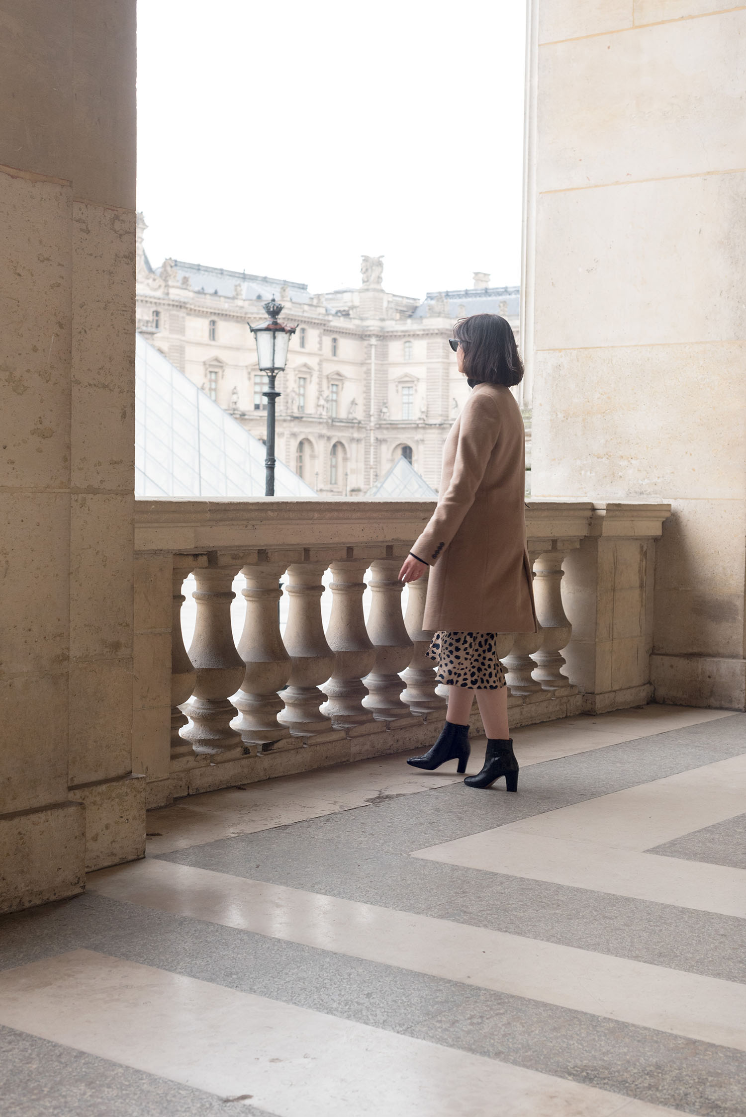 Top Winnipeg fashion blogger Cee Fardoe of Coco & Vera at the Louvre museum in Paris, wearing Minelli ankle boots and a Uniqlo camel coat