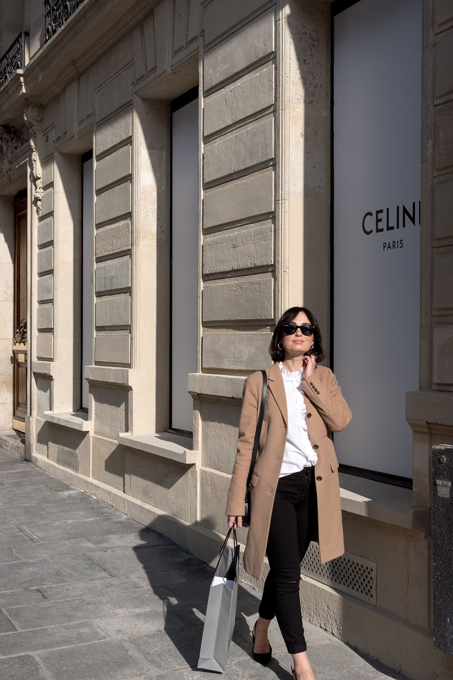 Top Canadian fashion blogger Cee Fardoe of Coco & Vera outside the Celine store in Paris, wearing a Sezane white blouse and Mavi block heel pumps