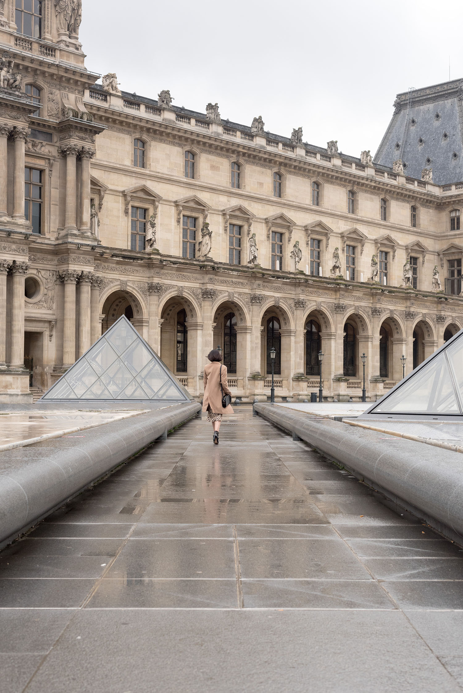 Top Winnipeg fashion blogger Cee Fardoe of Coco & Vera walks outside the Louvre museum in Paris, wearing Minelli ankle boots and carrying an APC half-moon handbag