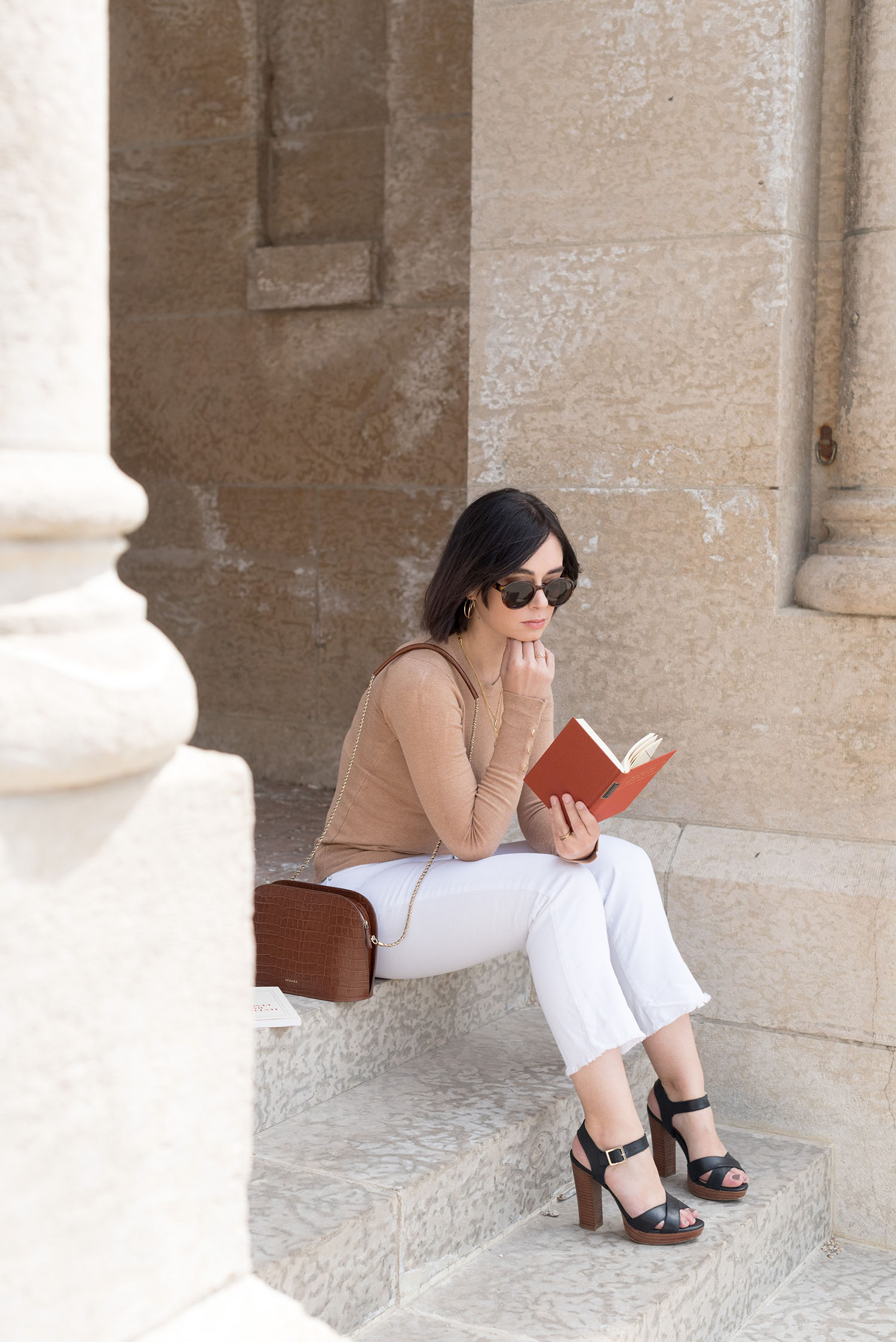Top Canadian fashion blogger Cee Fardoe of Coco & Vera sits reading, wearing Le Chateau sandals and & Other Stories sunglasses