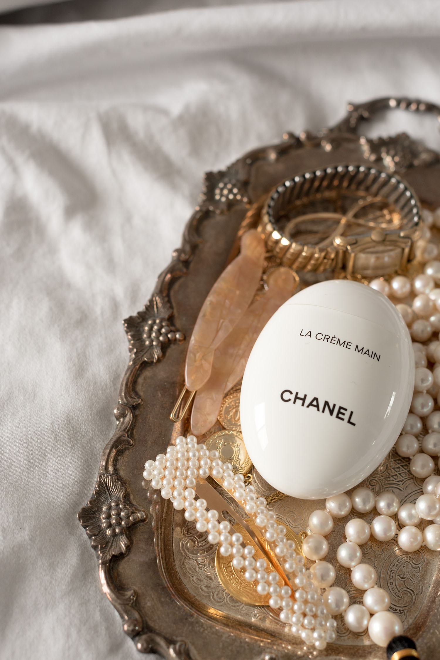 Chanel Beauty creme de main, along with pearl accessories, on a silver tray, as captured by top Canadian beauty blogger Cee Fardoe of Coco & Vera