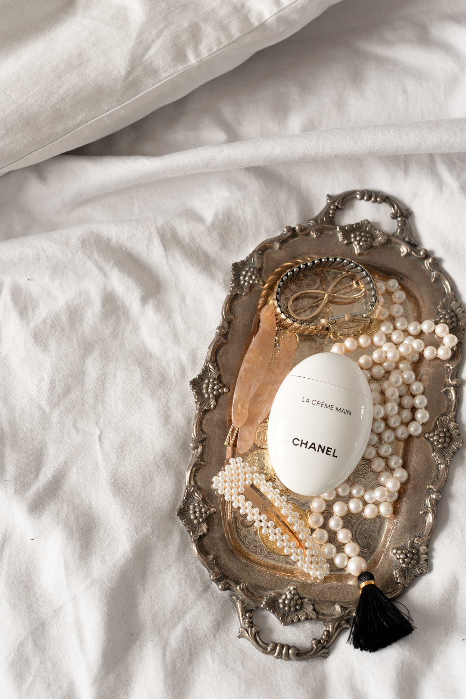 Chanel Beauty creme de main on a silver tray with pearl accessories, as captured by top Canadian beauty blogger Cee Fardoe of Coco & Vera