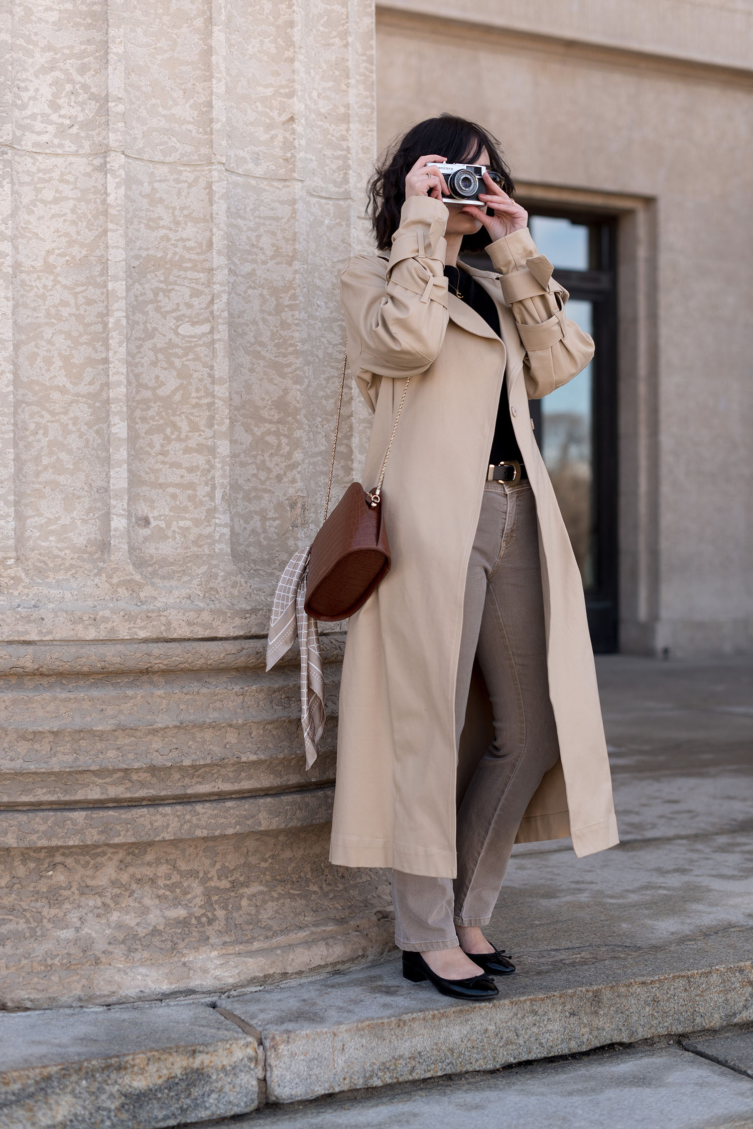Top Winnipeg fashion blogger Cee Fardoe of Coco & Vera stands at the Manitoba Legislature wearing an H&M trench coat and carrying a Sezane handbag
