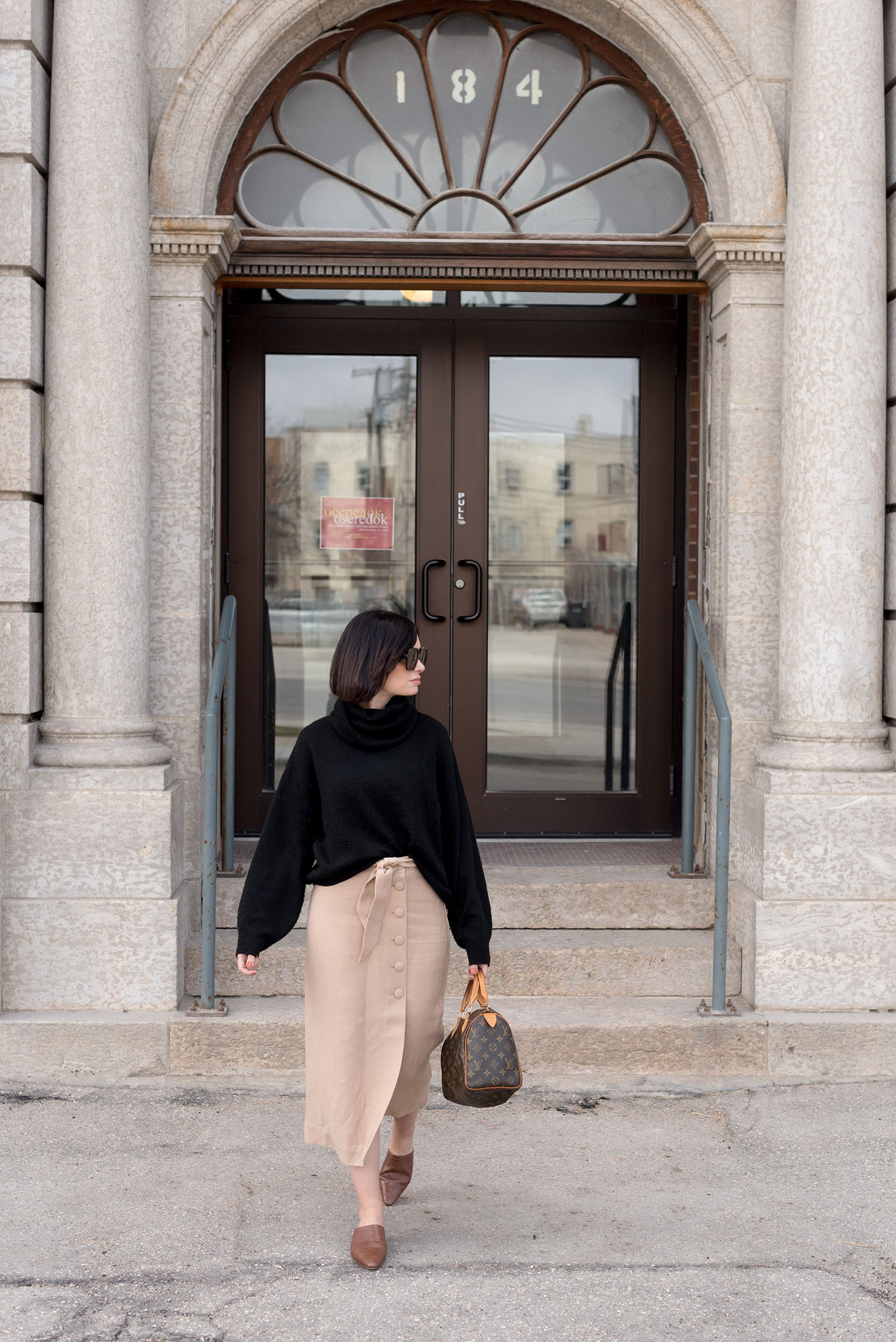 Top Canadian fashion blogger Cee Fardoe of Coco & Vera walks outside of Oseredok in Winnipeg, wearing an & Other Stories midi skirt and Oak + Fort mules
