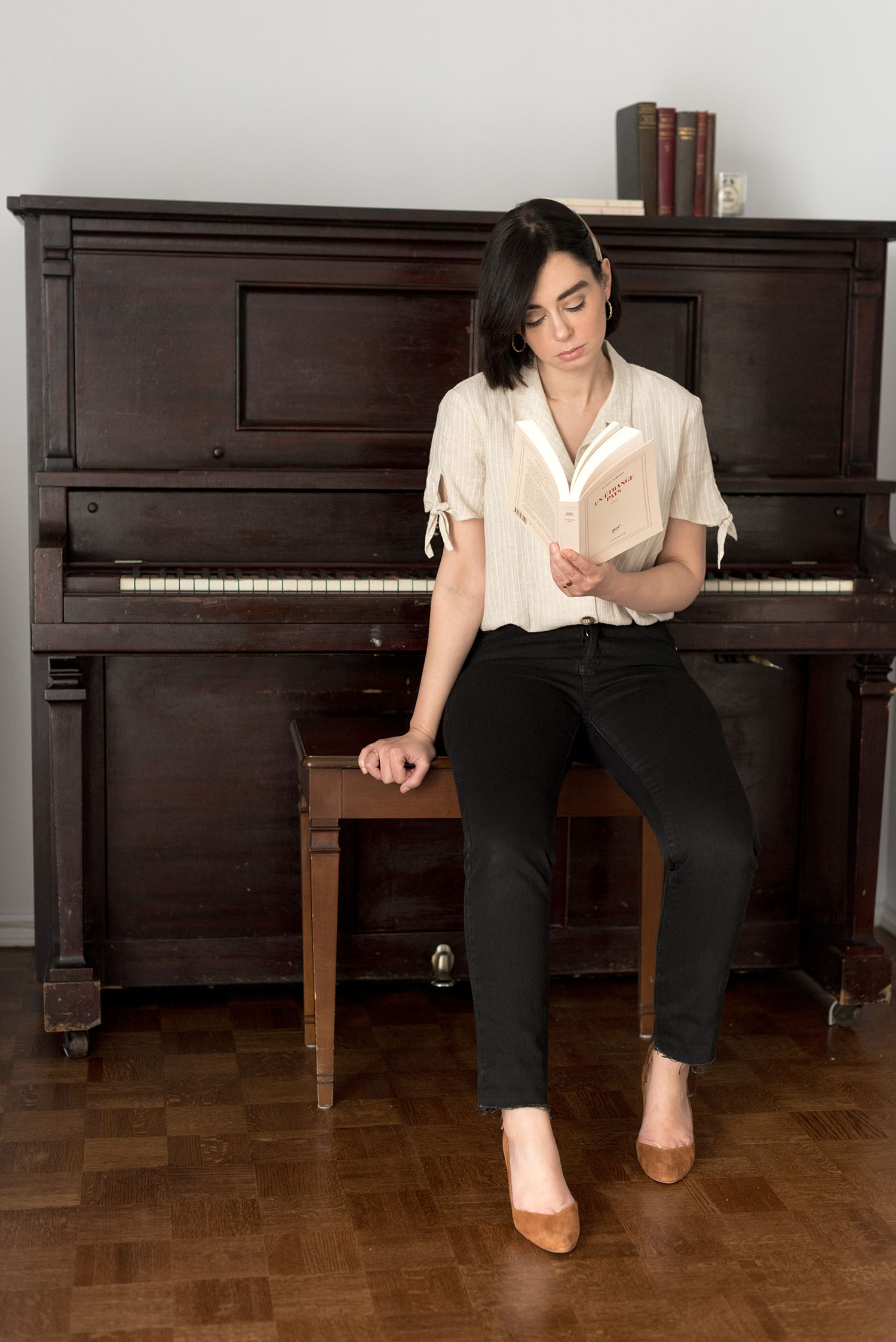 Top Winnipeg fashion blogger Cee Fardoe of Coco & Vera sits in front of a piano wearing Sezane heels and a Mango blouse