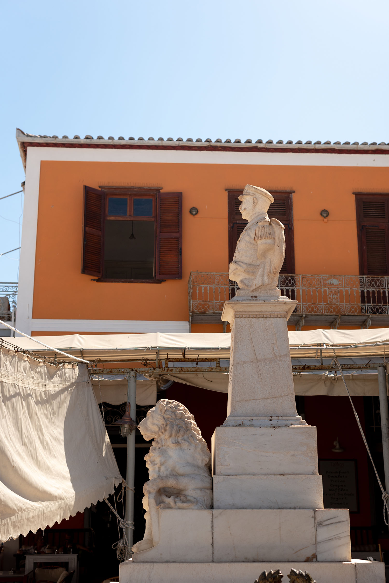 Coco & Vera - Marble statue in sunny square on Hydra, Greece
