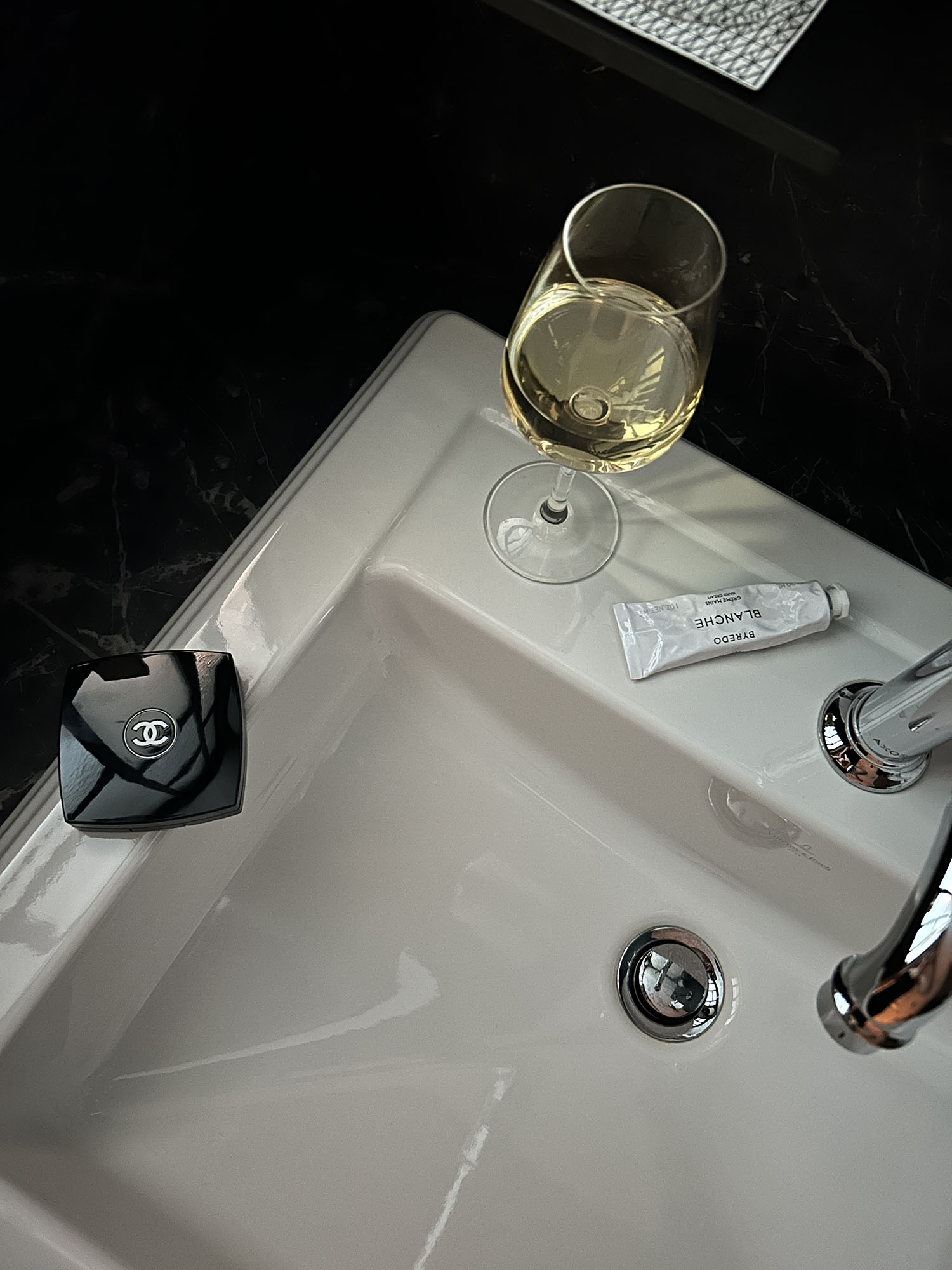 Coco & Voltaire - Chanel compact, Byredo hand cream and white wine by a sink