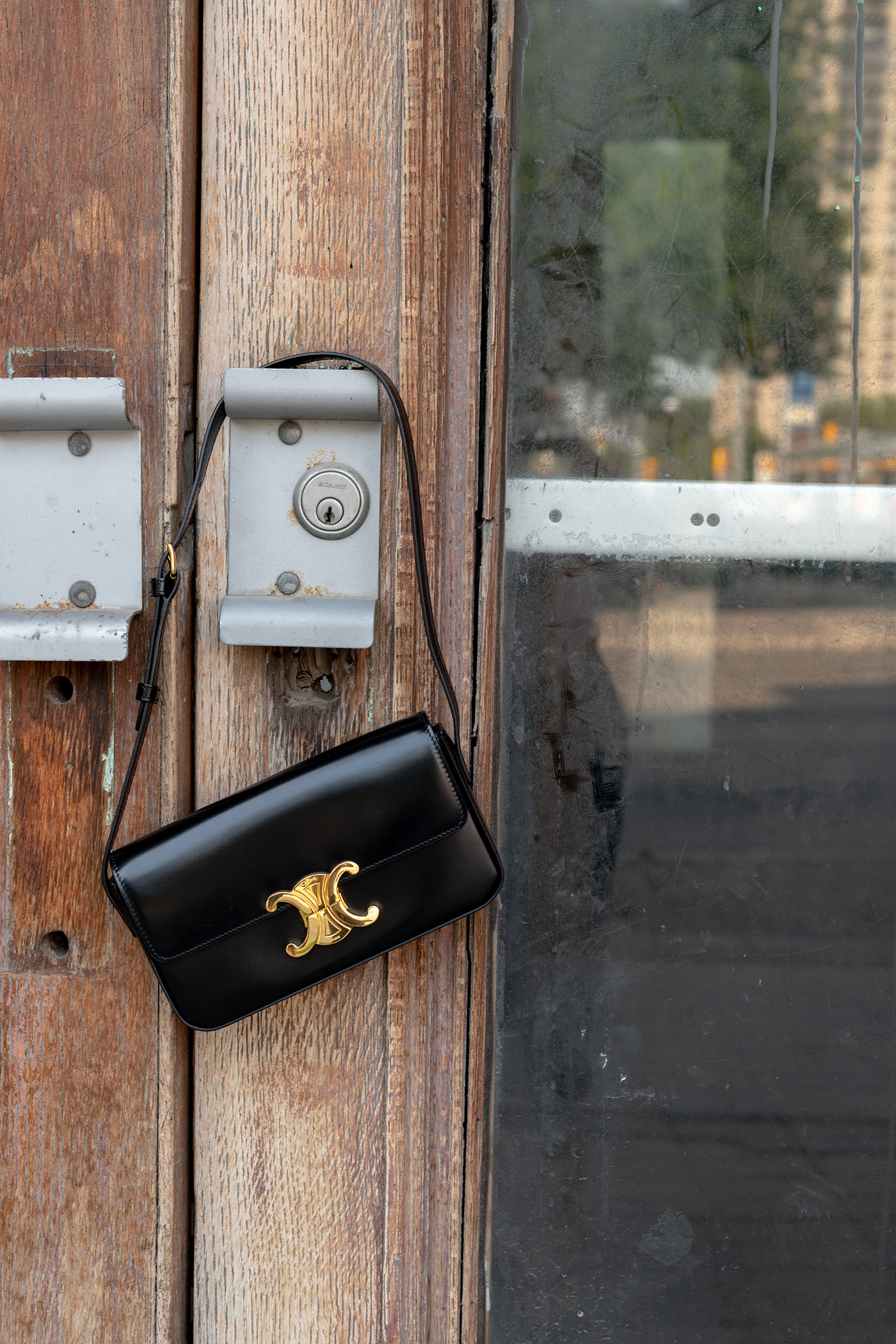 Coco & Voltaire - Celine Triomphe handbag hanging on metal door handle