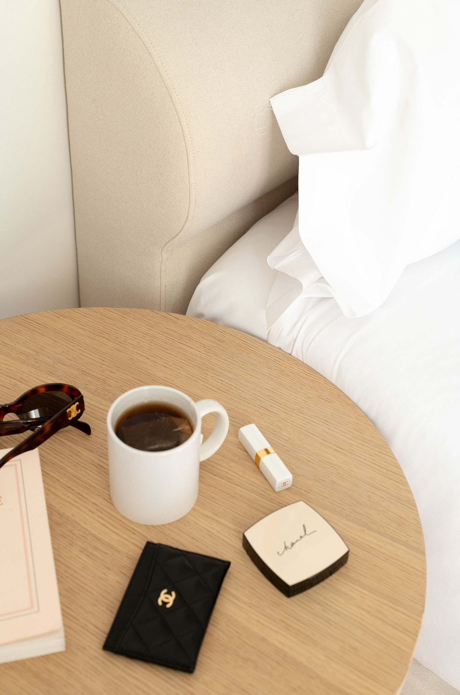 Coco & Voltaire - Celine Triomphe sunglasses, Chanel card holder and teacup on bedside table
